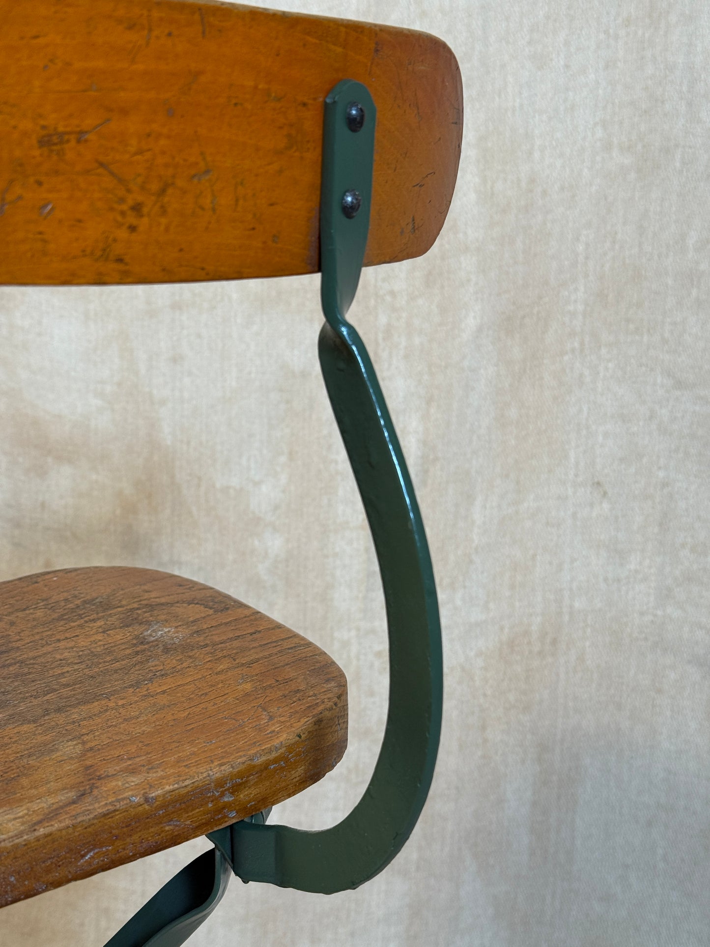 Vintage industrial machinist chair with green steel frame, wooden seat. 