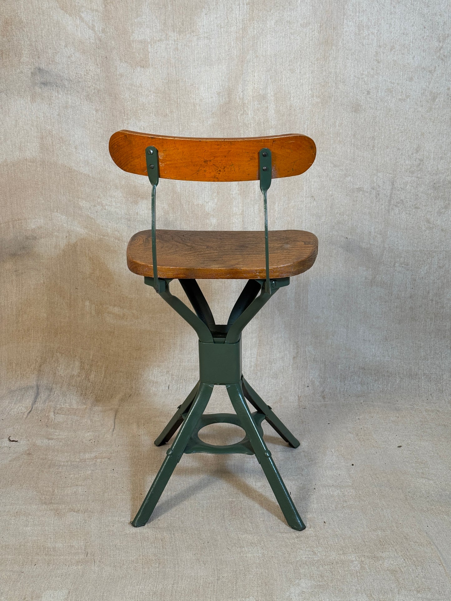 Vintage industrial machinist chair with green steel frame, wooden seat. 