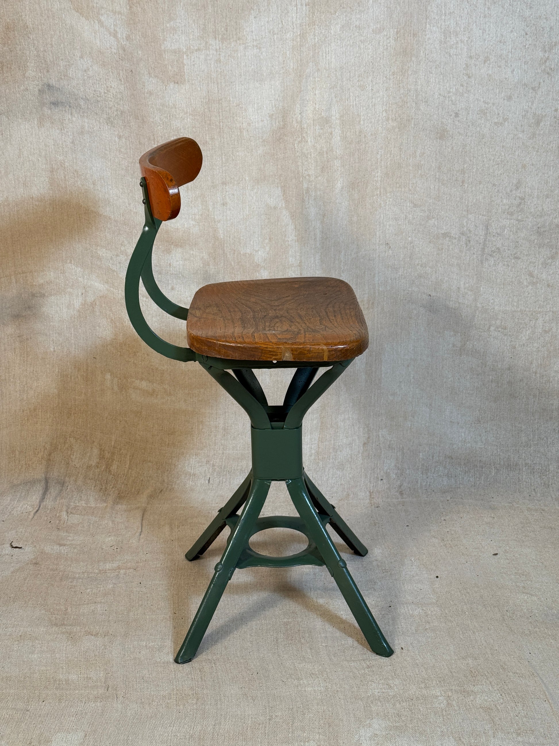 Vintage industrial machinist chair with green steel frame, wooden seat. 