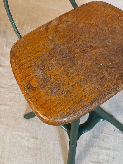 Vintage industrial machinist chair with green steel frame, wooden seat. 