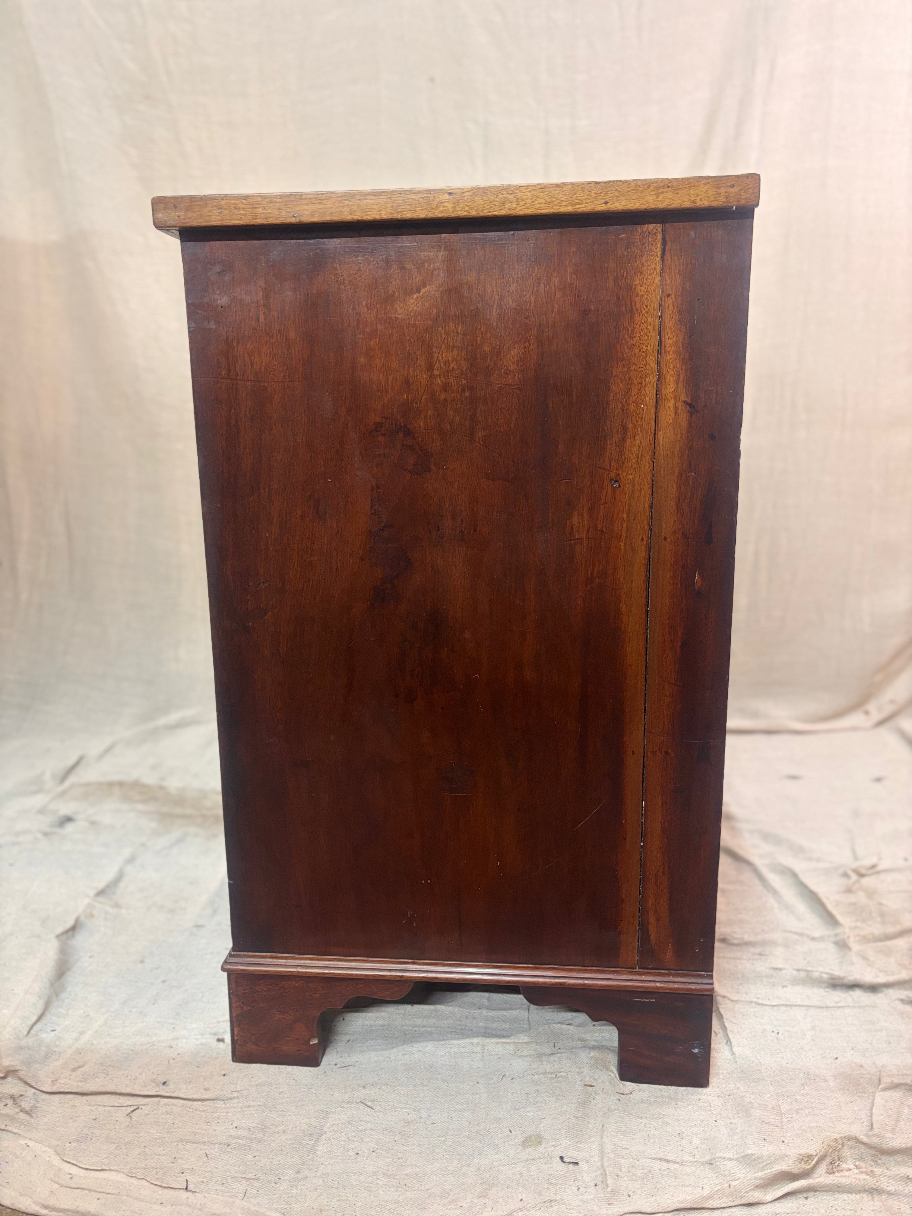 Wooden cabinet with a worn finish on a textured fabric background