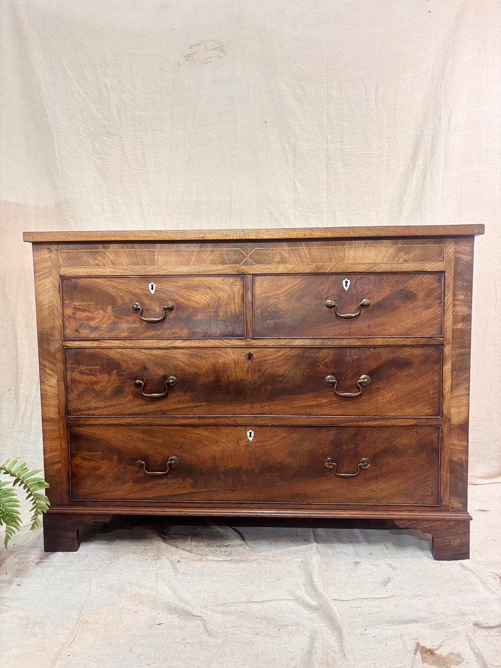 Wooden dresser with four drawers on a neutral background