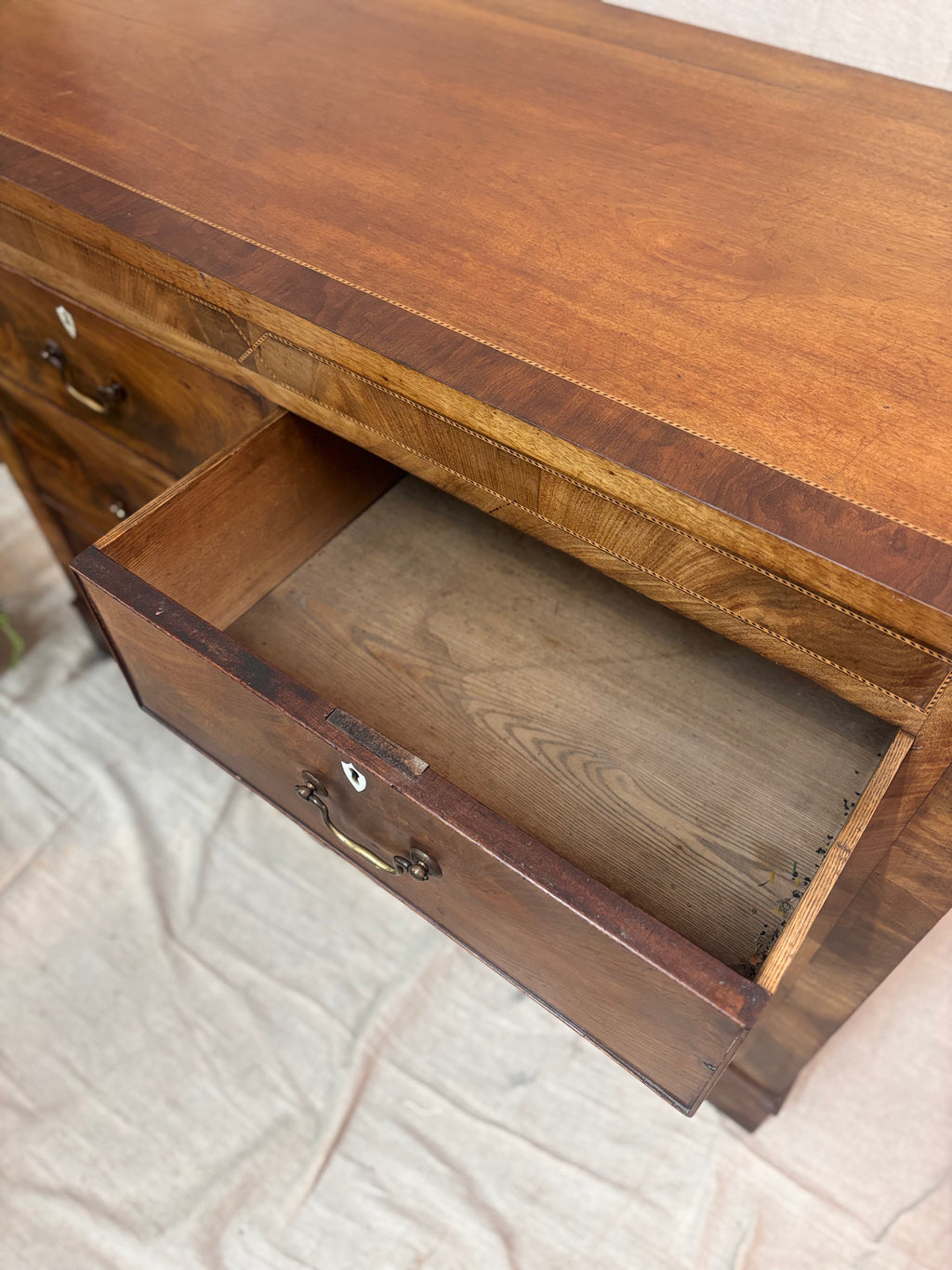 Wooden chest of drawers with an open drawer on a textured surface