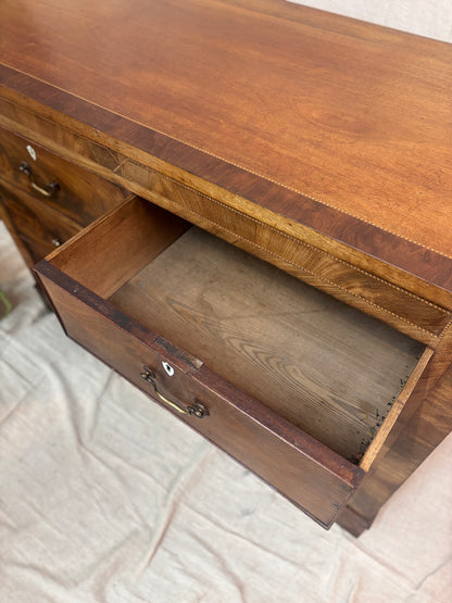 Wooden chest of drawers with an open drawer on a textured surface