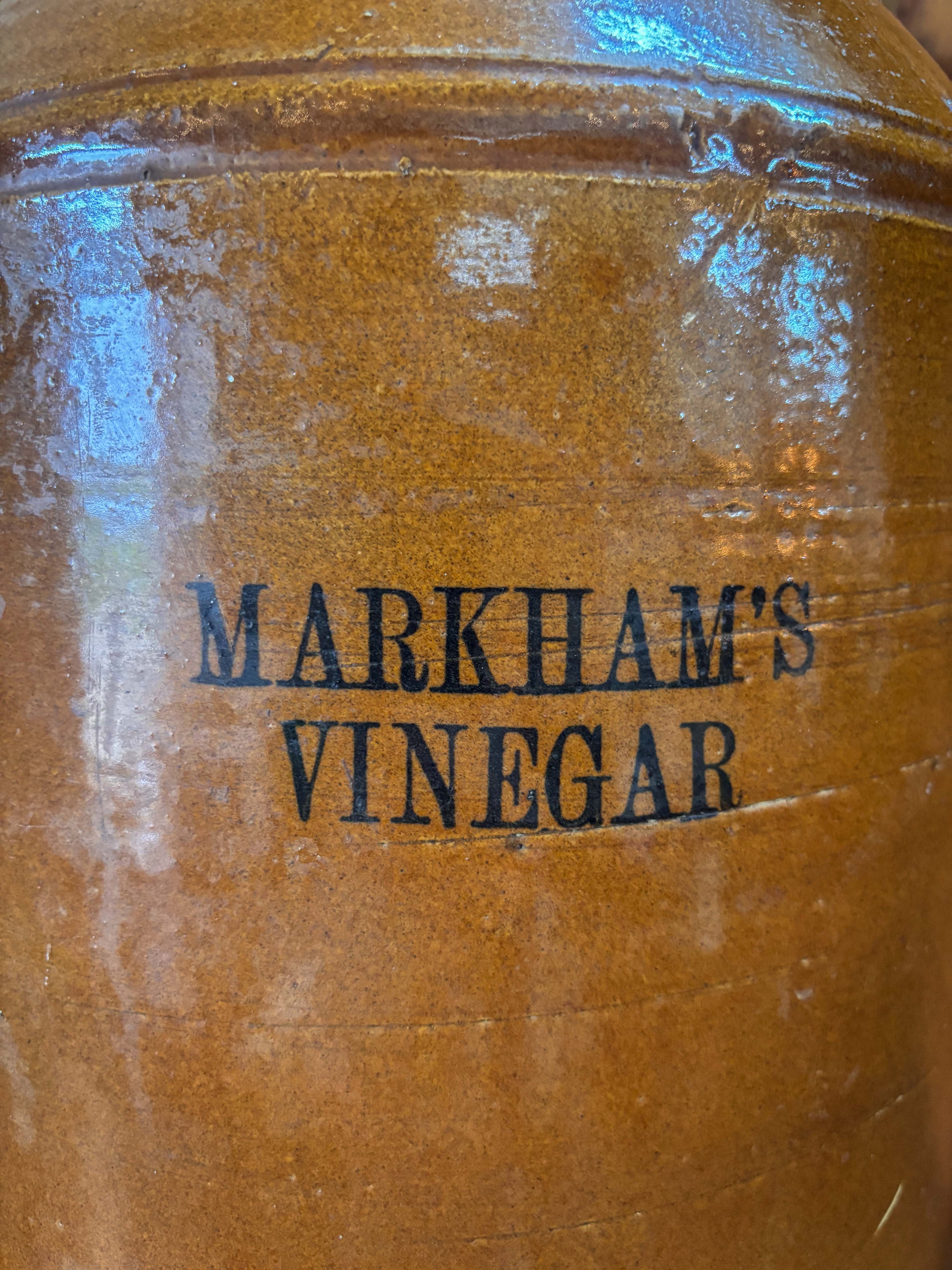 Brown jar with 'Markham's Vinegar' branding on a reflective surface
