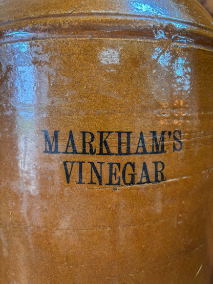 Brown jar with 'Markham's Vinegar' branding on a reflective surface