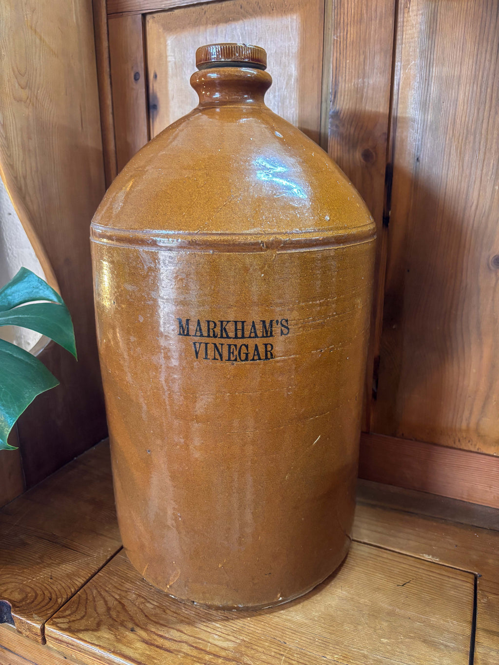Large brown ceramic jar labeled 'Markham's Vinegar' on a wooden surface.