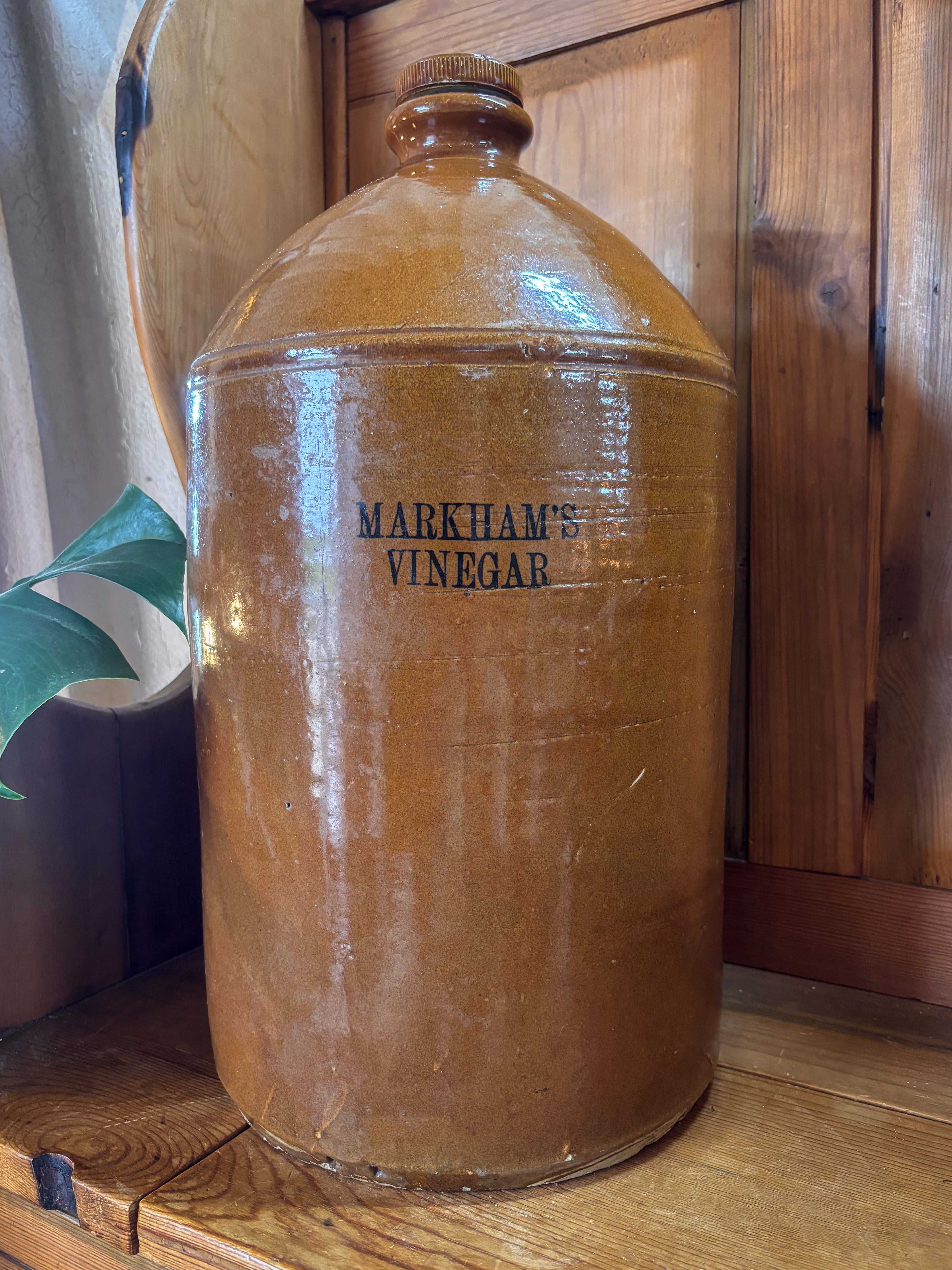 Large clay jar labeled 'Markham's Vinegar' on a wooden surface.