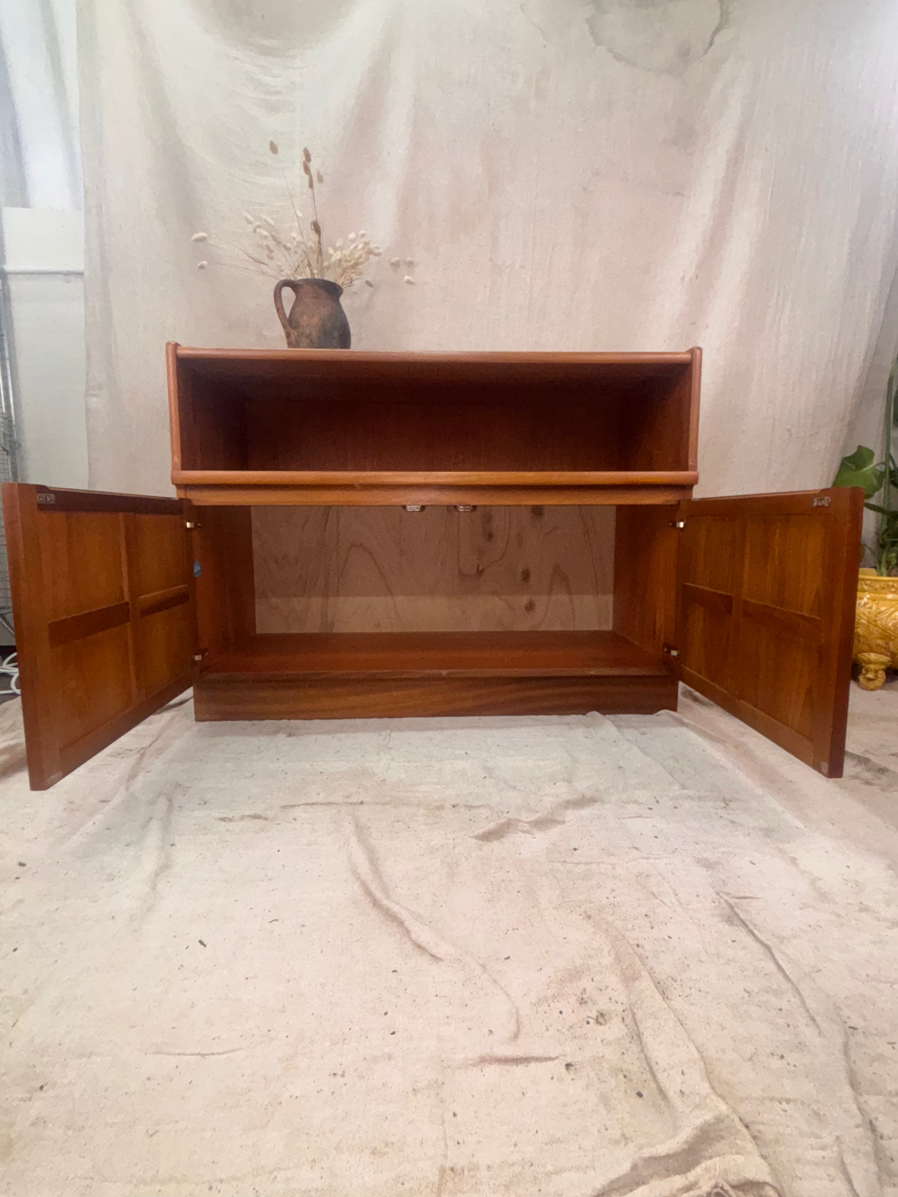 A Mid Century Modern Sideboard with cupboard doors open on a cream background. 