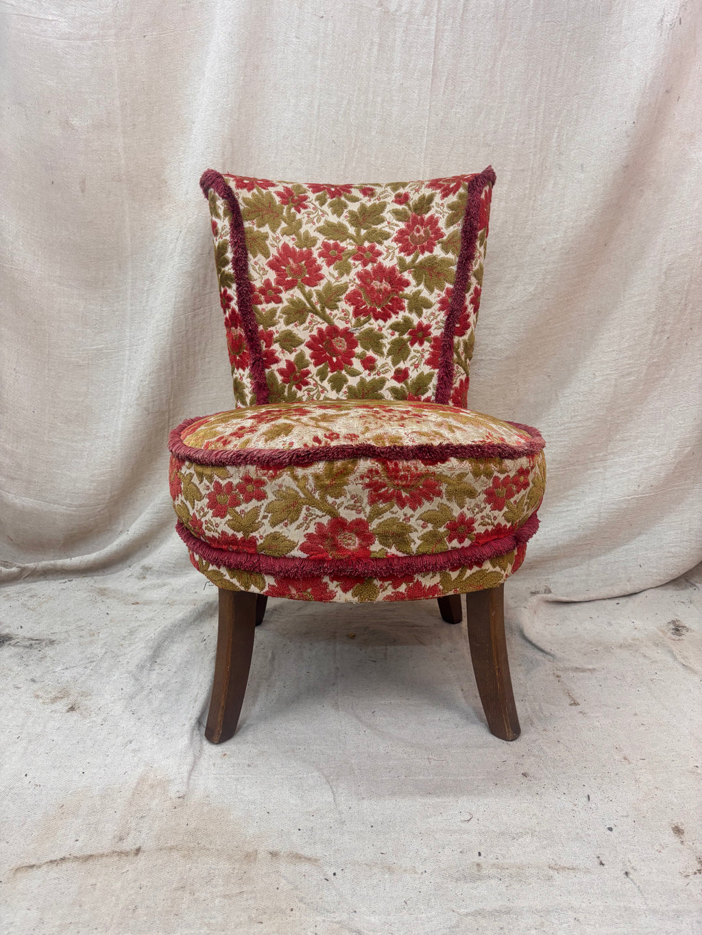 Floral patterned chair with wooden legs on a plain background