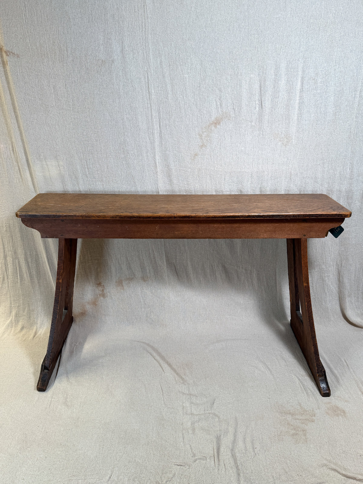 Traditional oak organ bench in the Gothic style, with a wide wooden seat and angled side frames. Suitable for an organ or as decorative seating.