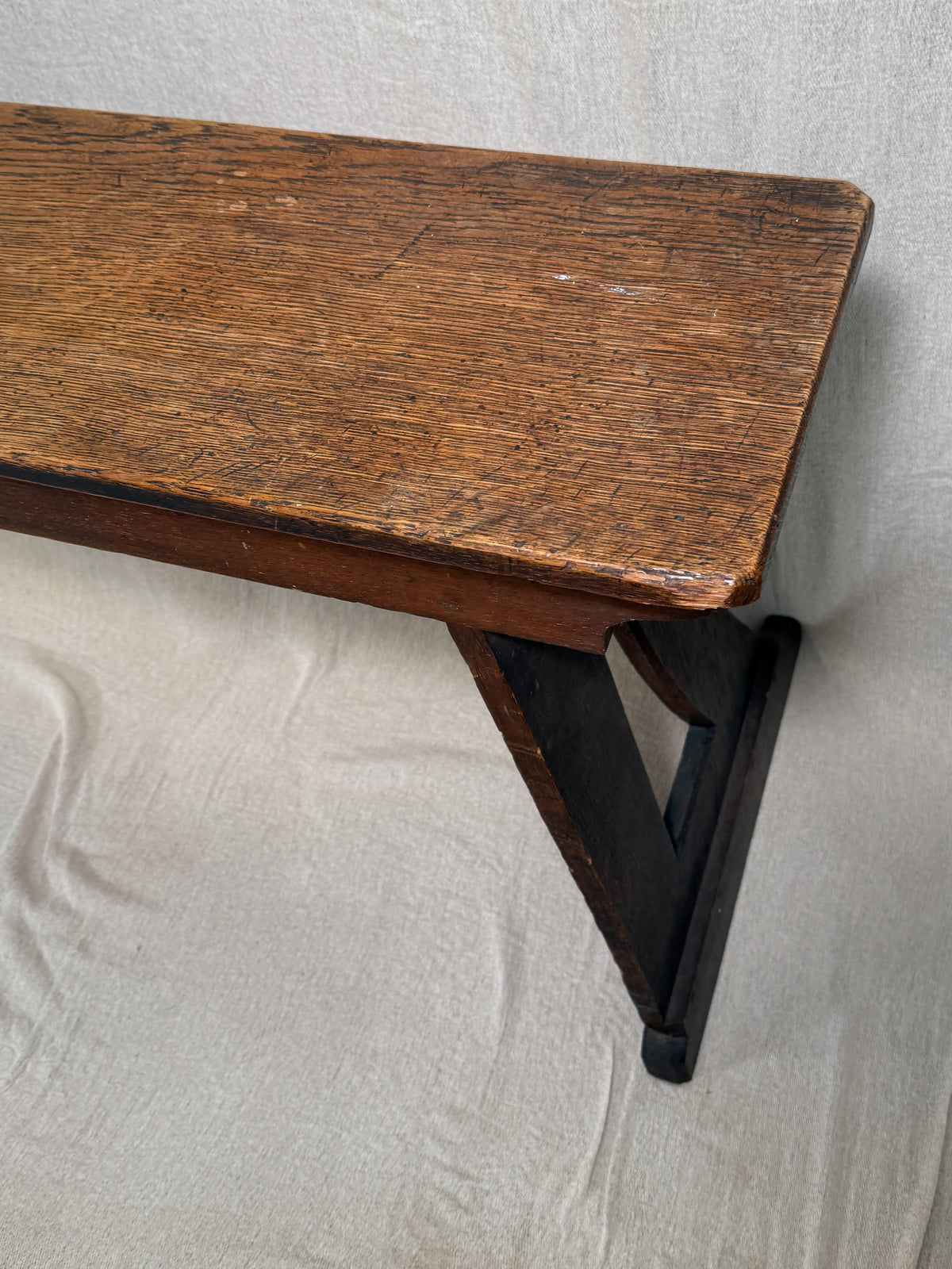 Traditional oak organ bench in the Gothic style, with a wide wooden seat and angled side frames. 