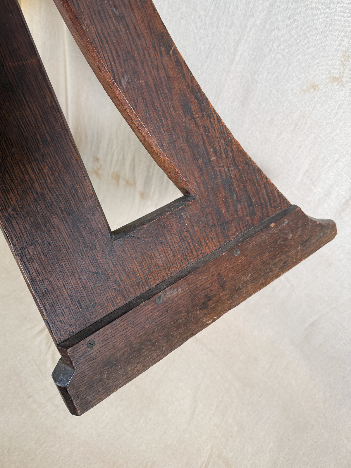 Traditional oak organ bench in the Gothic style, with a wide wooden seat and angled side frames. 