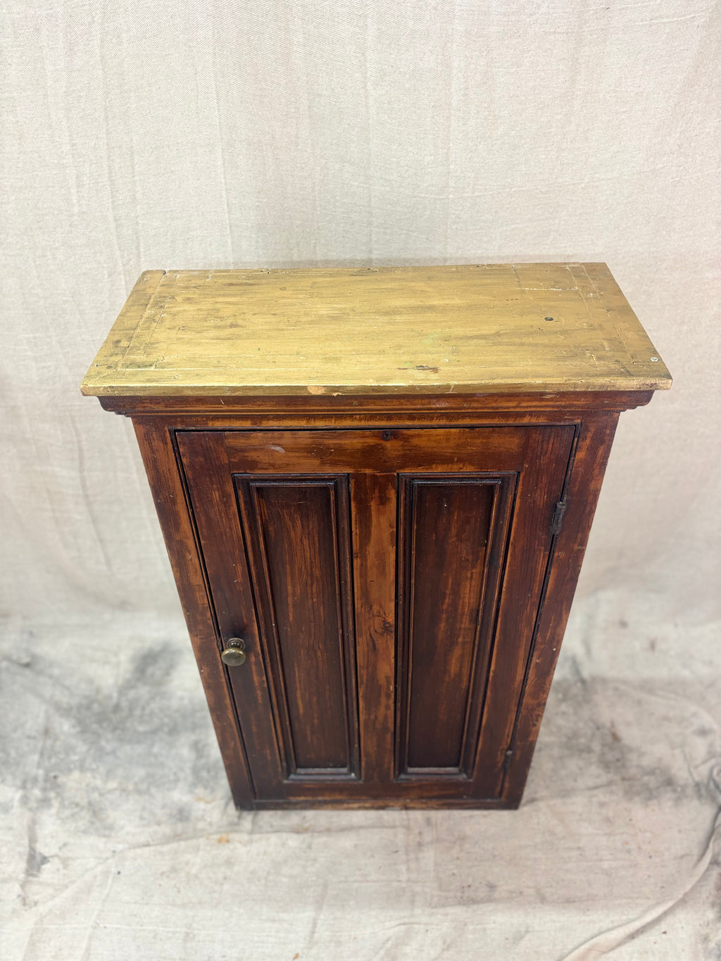 Wooden cabinet with a yellowish top on a textured beige background