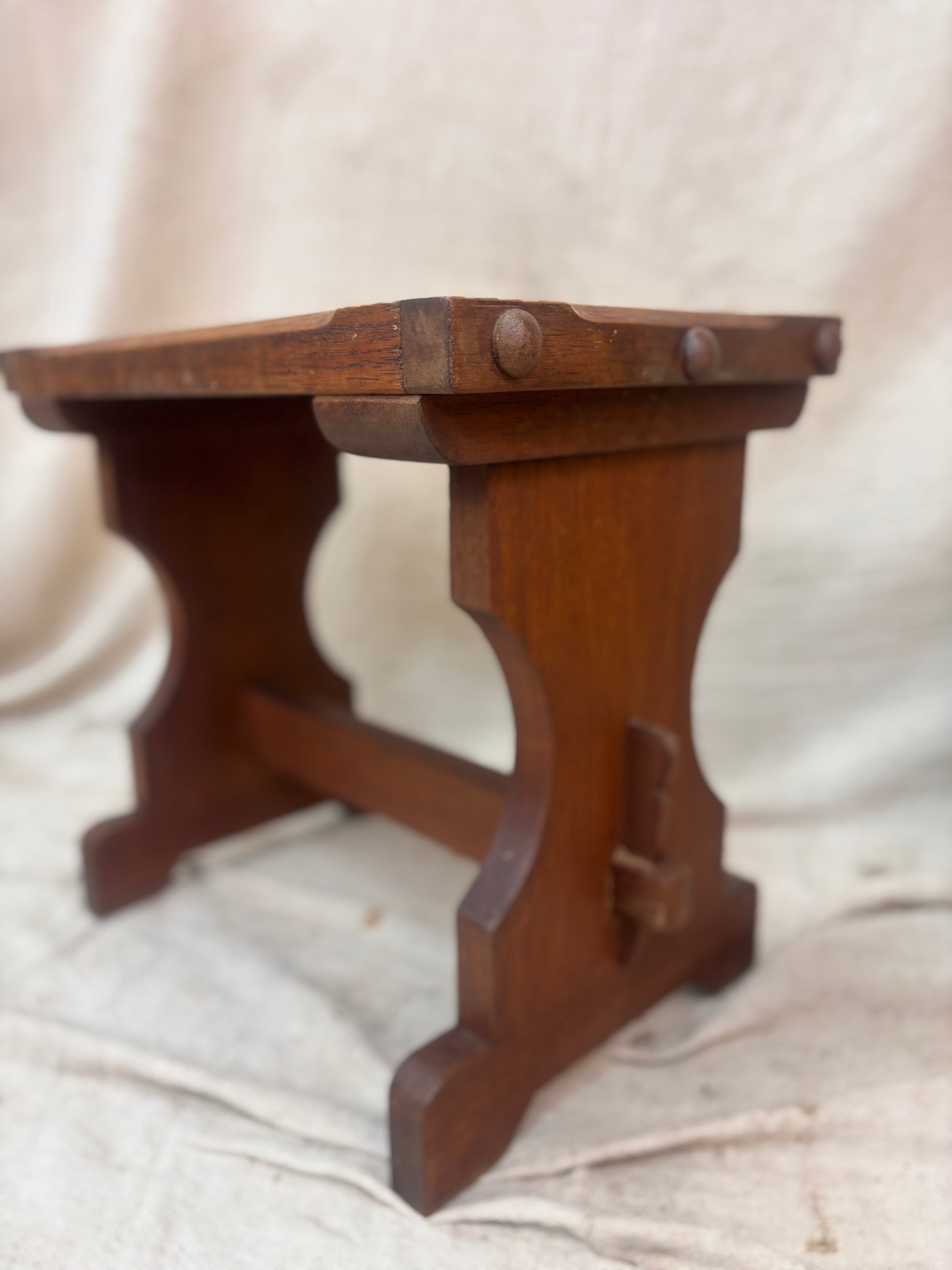 Wooden stool with a rustic design on a beige fabric background