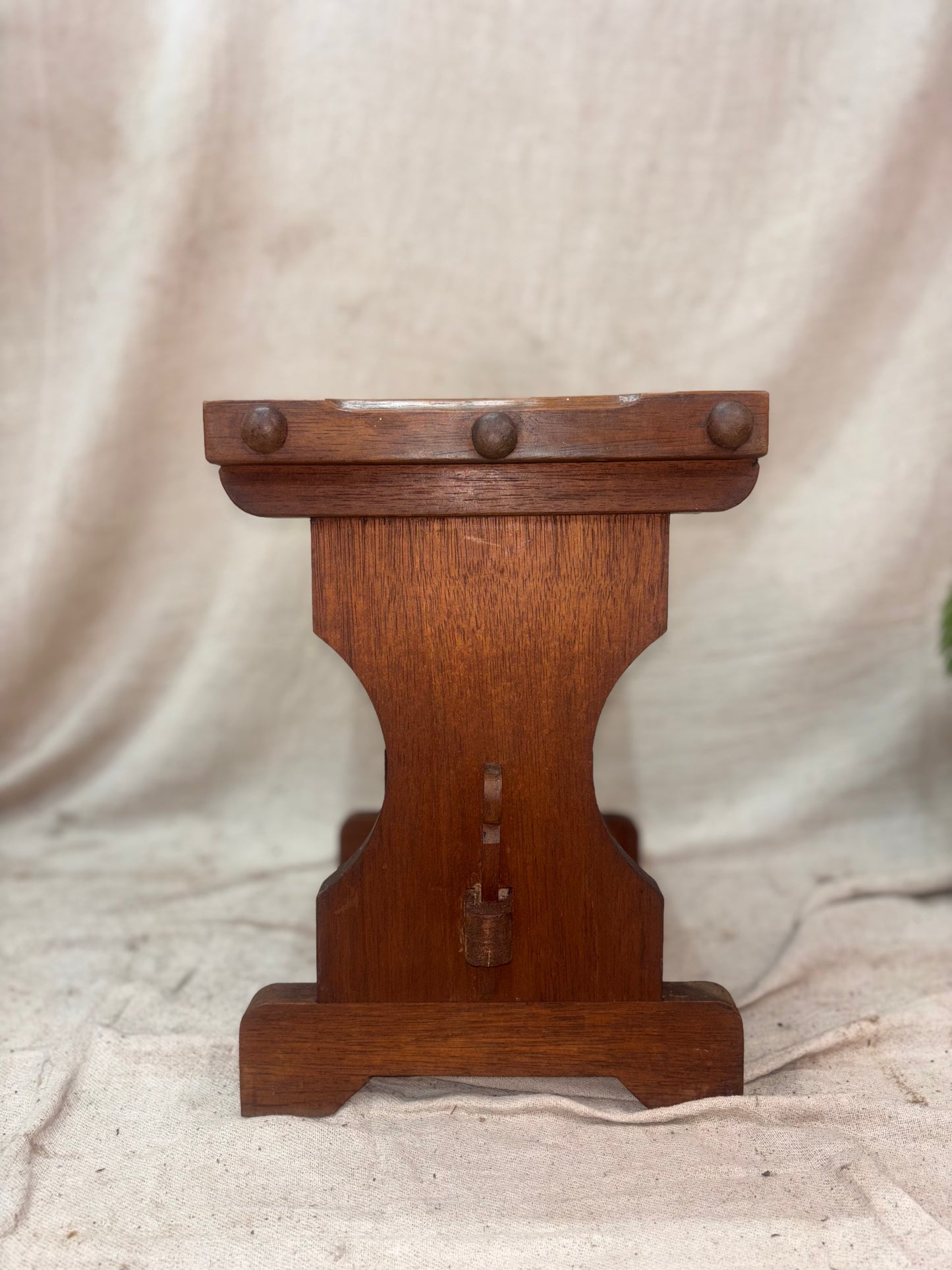 Wooden stool with decorative elements on a beige fabric background