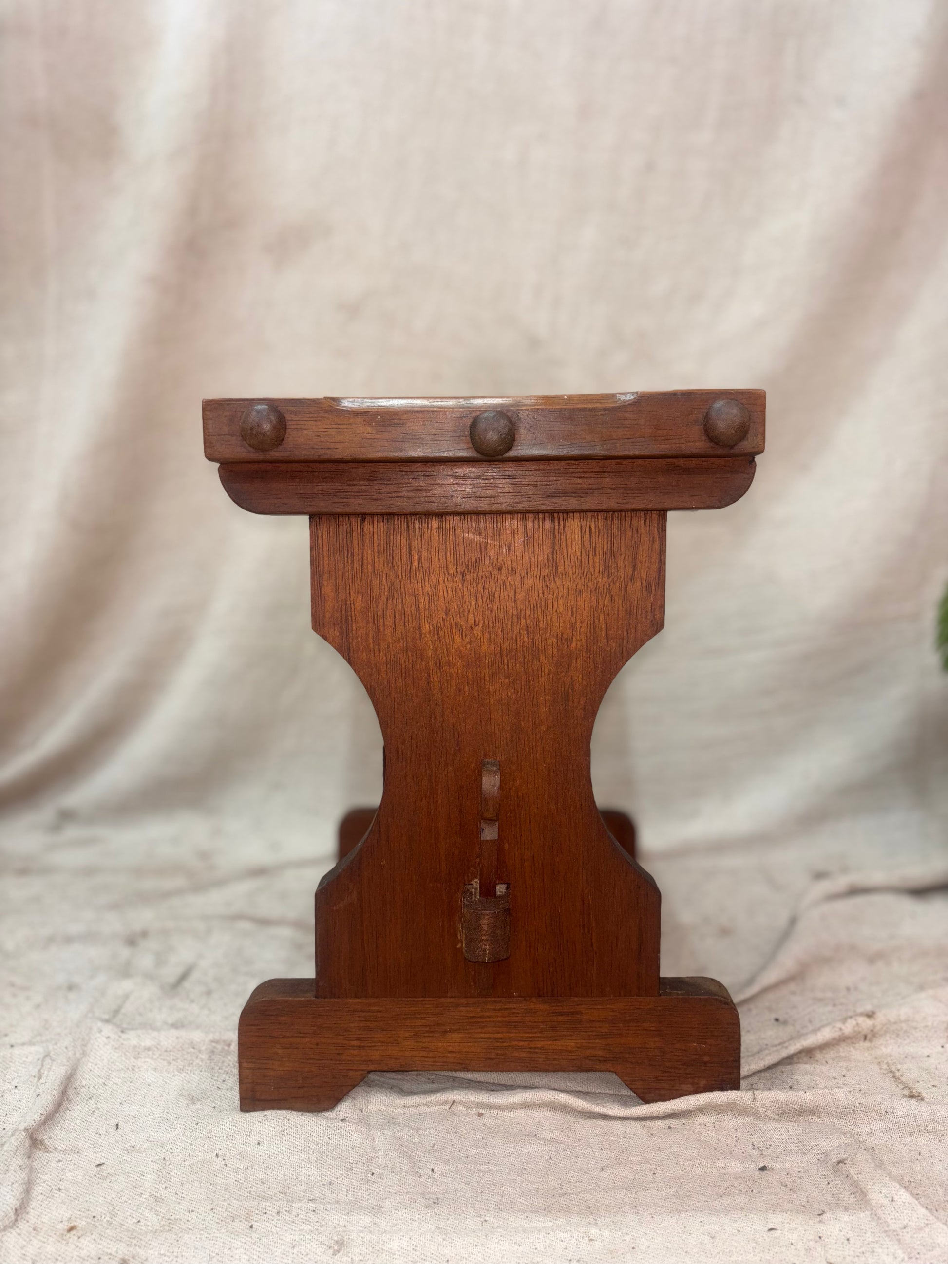 Wooden stool with decorative elements on a beige fabric background