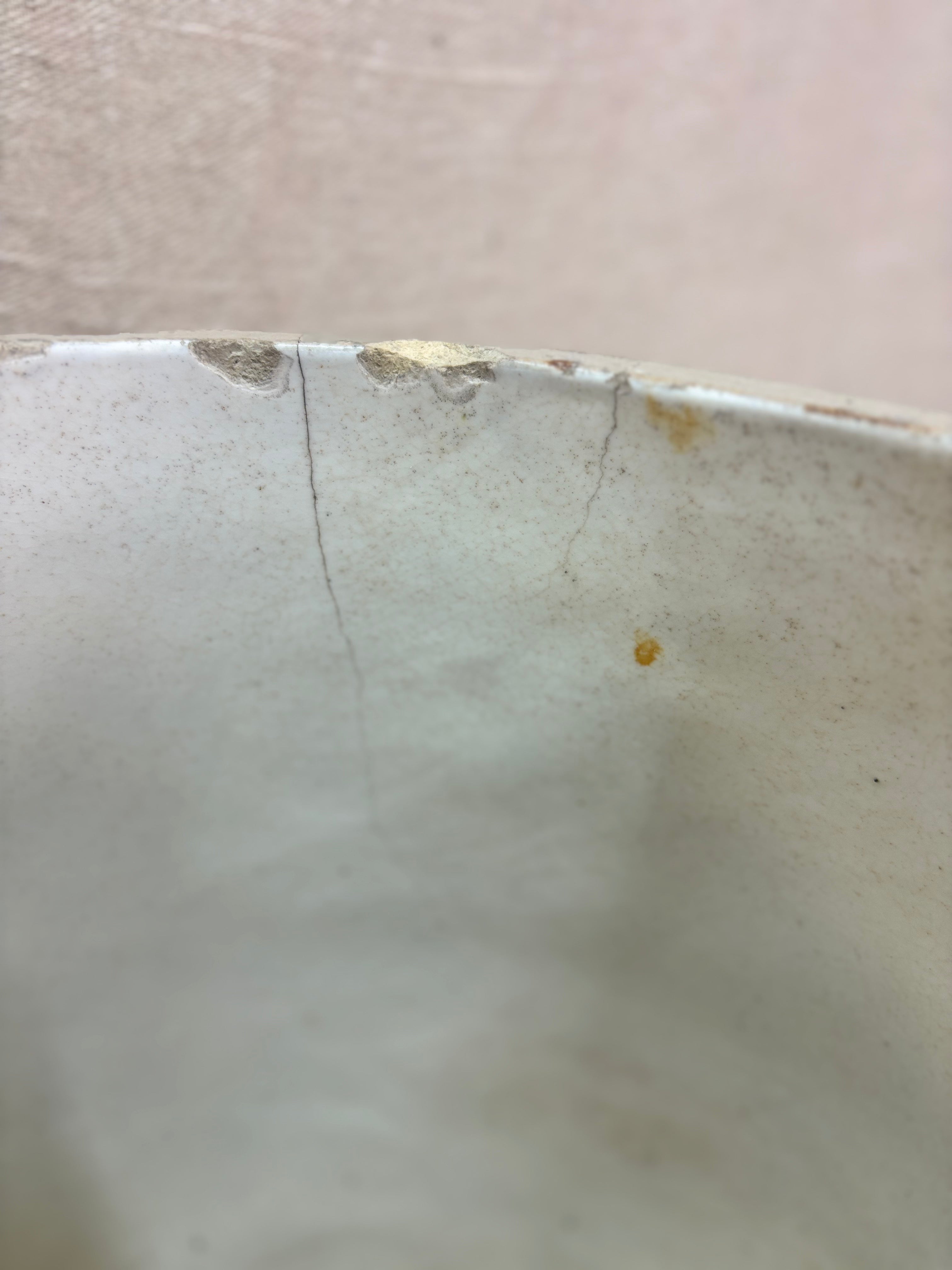 Close-up of a ceramic bowl with a crack and residue on a beige background