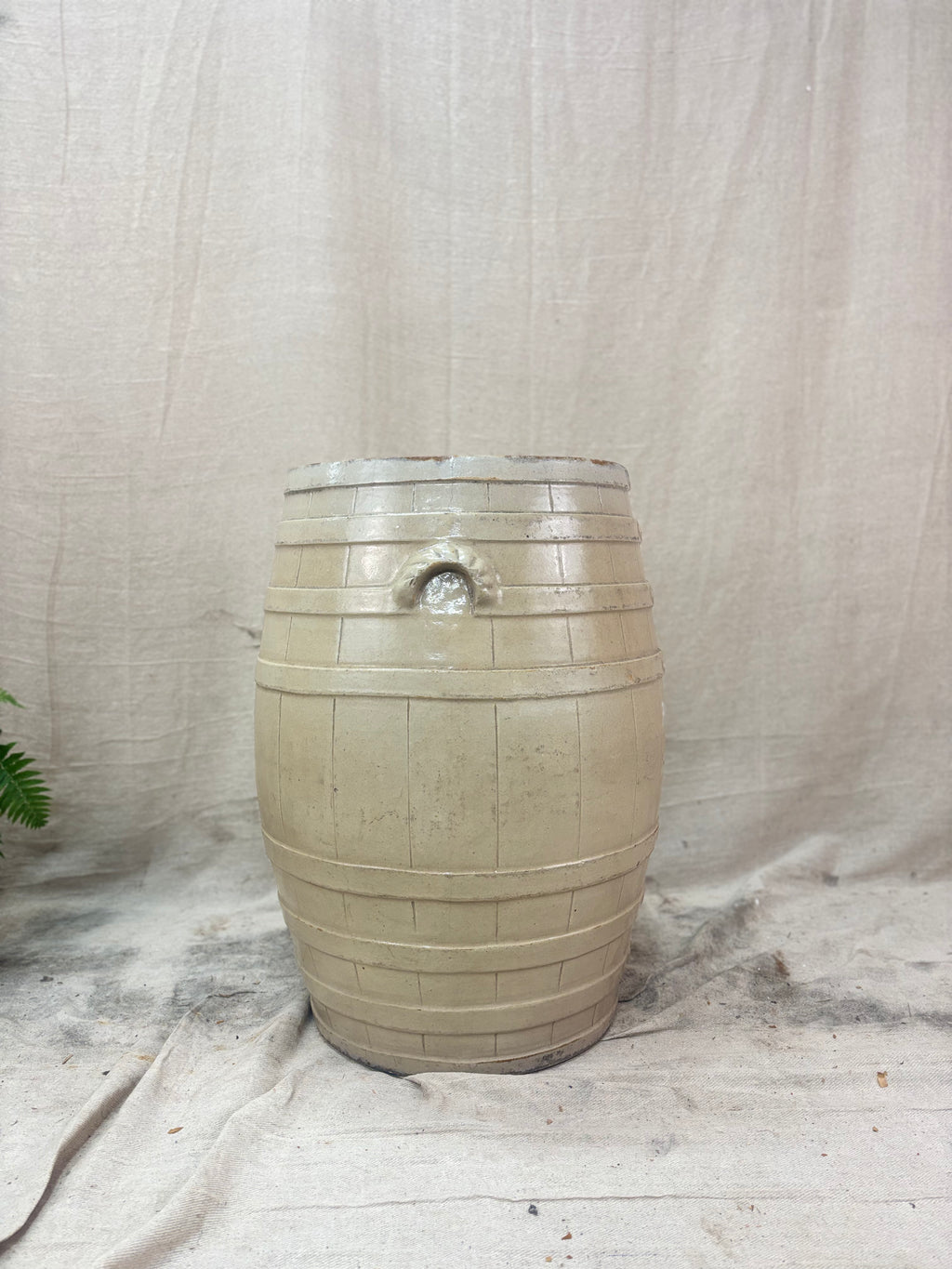 Beige ceramic barrel on a textured fabric background