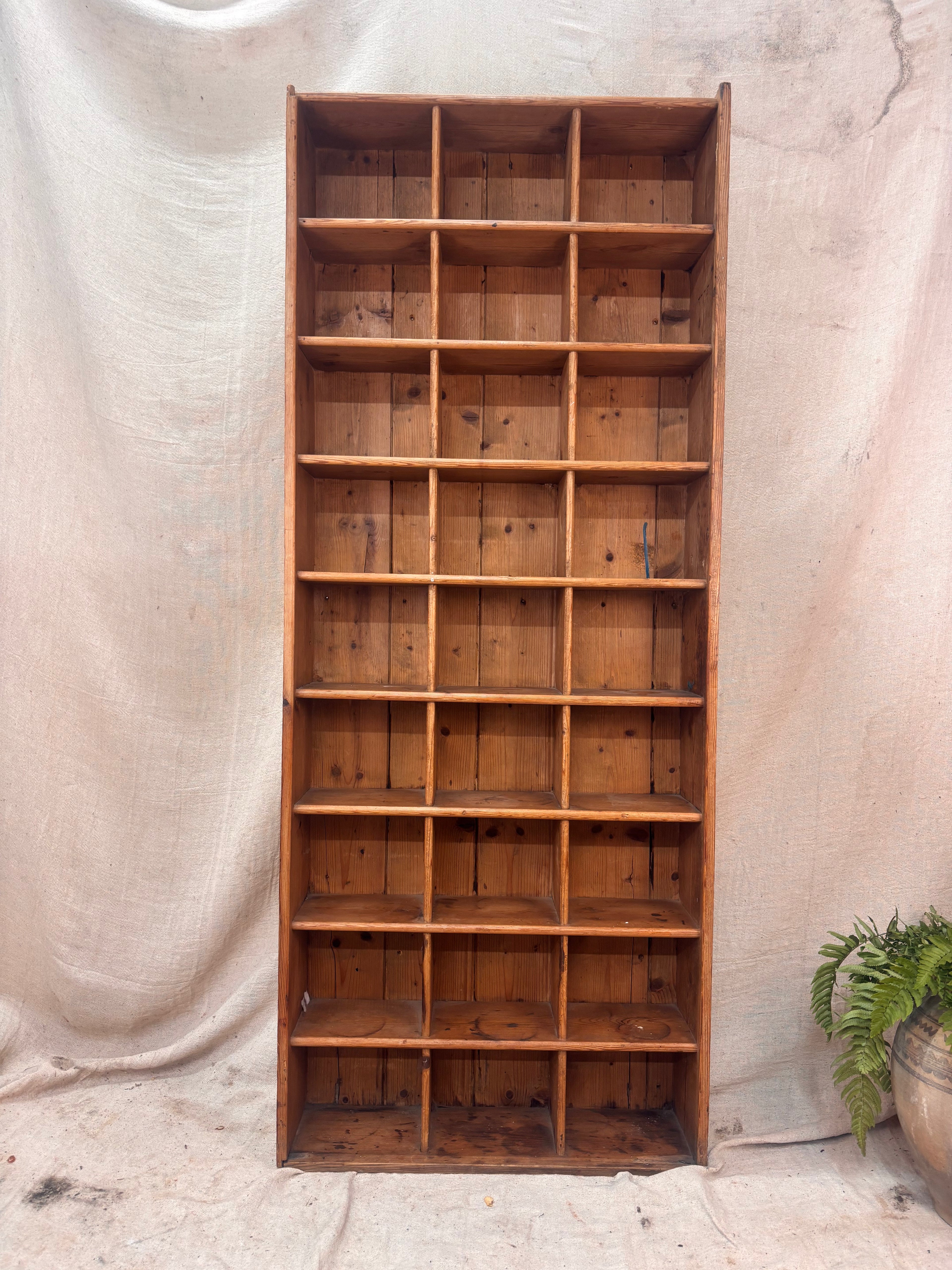 Wooden pigeon hole shelf against a textured beige curtain