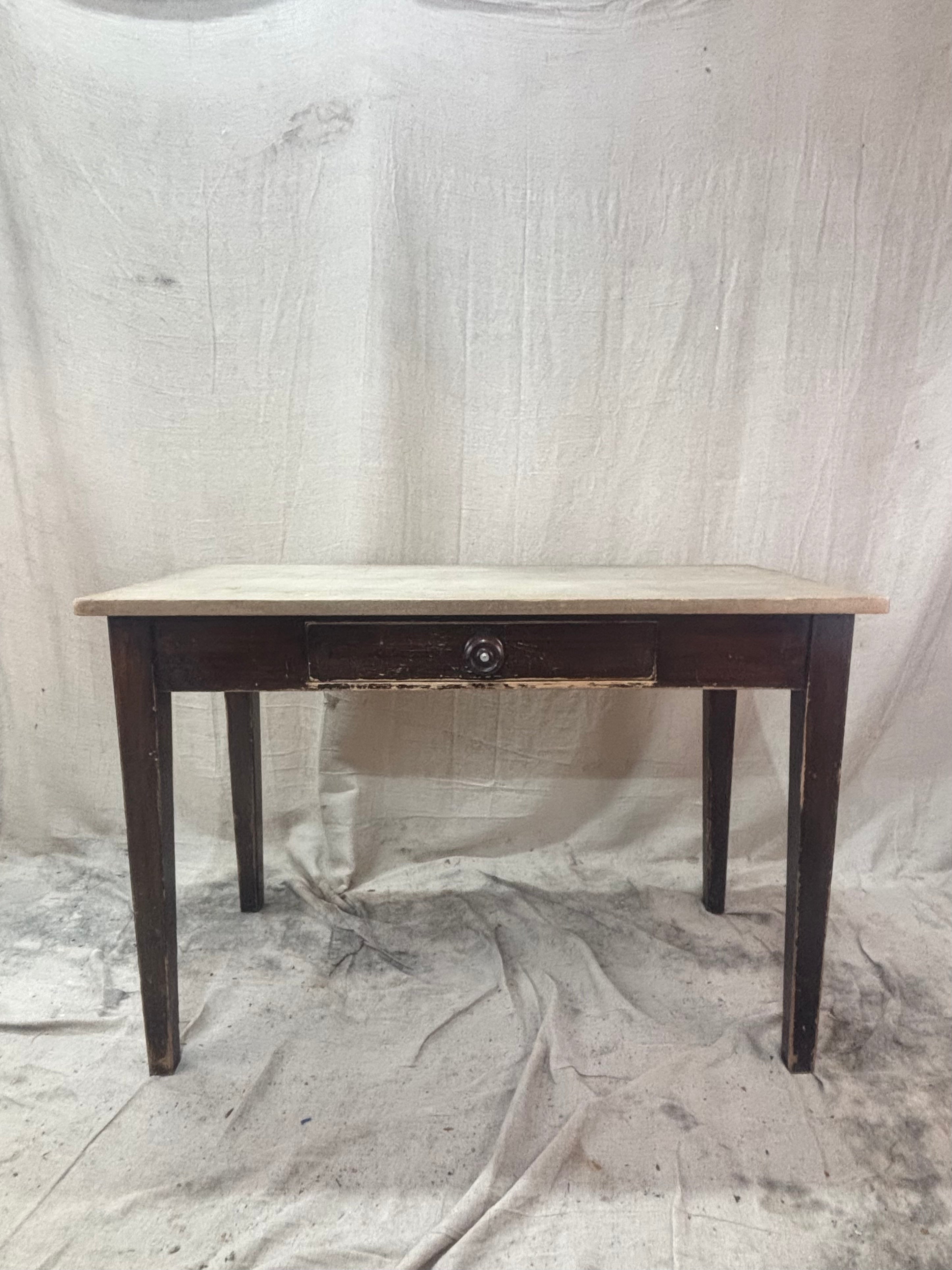small pine table with dark legs and a light top on a light cloth background