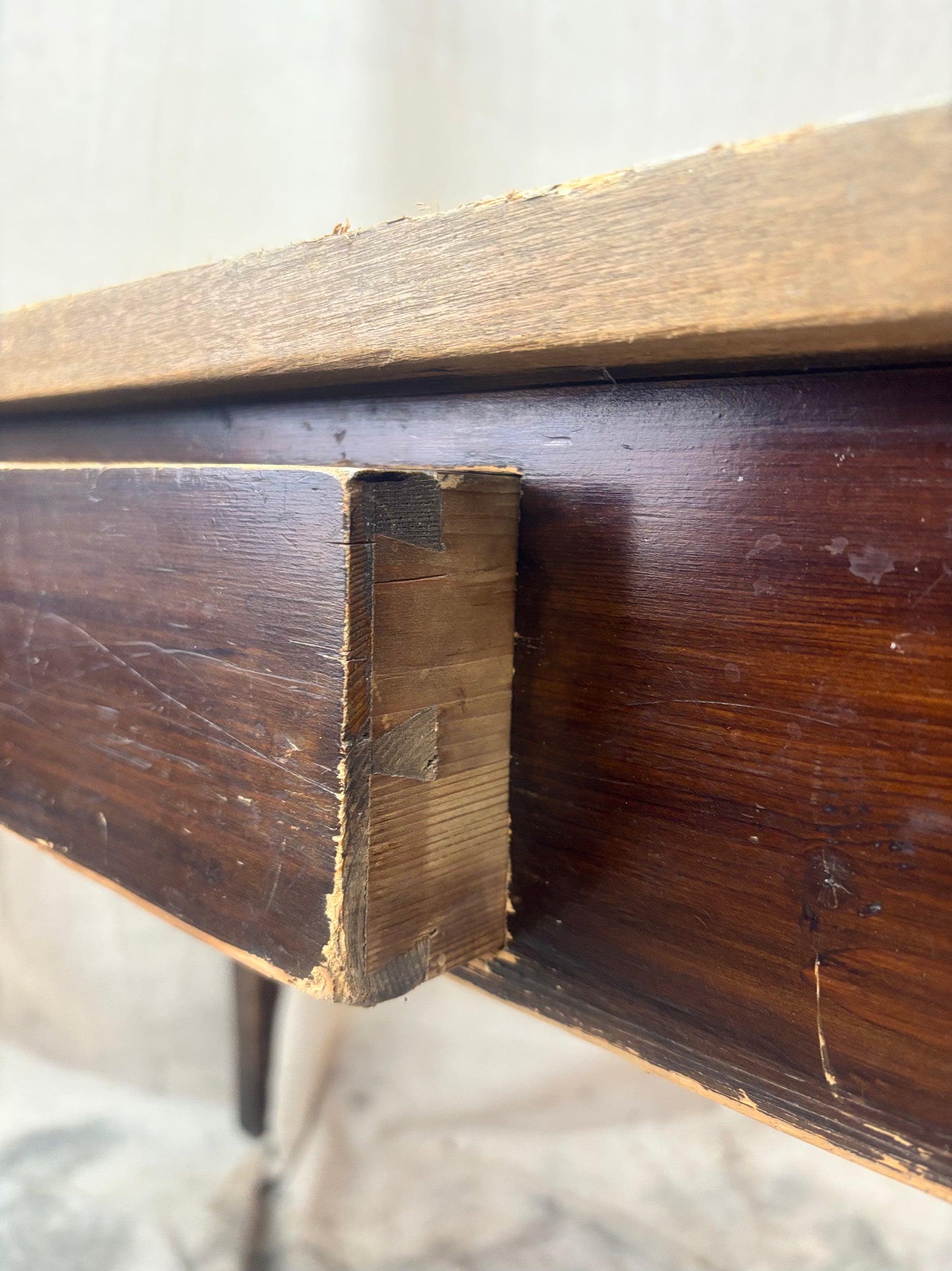 Close-up of a wooden furniture corner with visible grain and texture.
