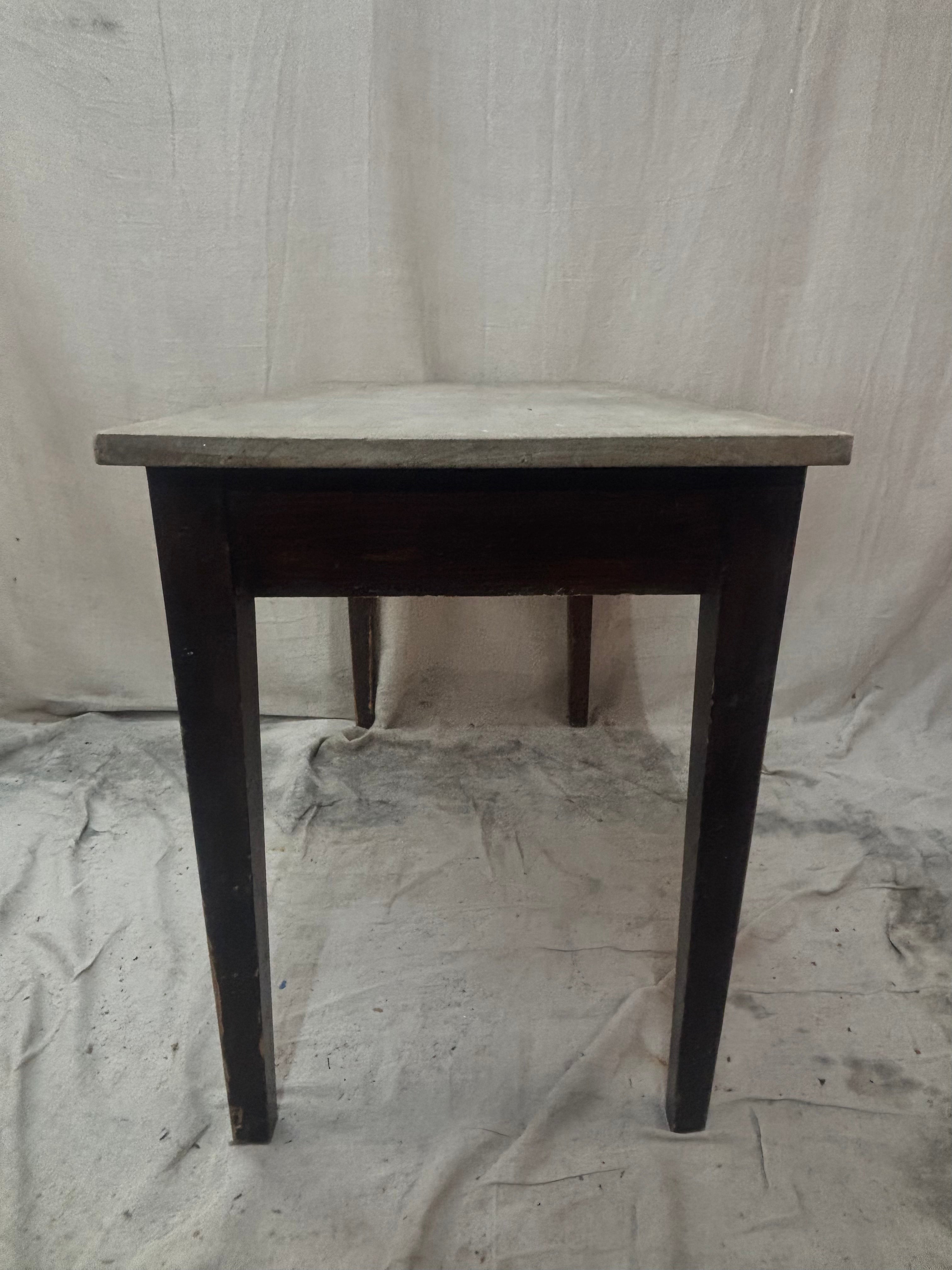small pine table with dark legs and a light top on a light cloth background