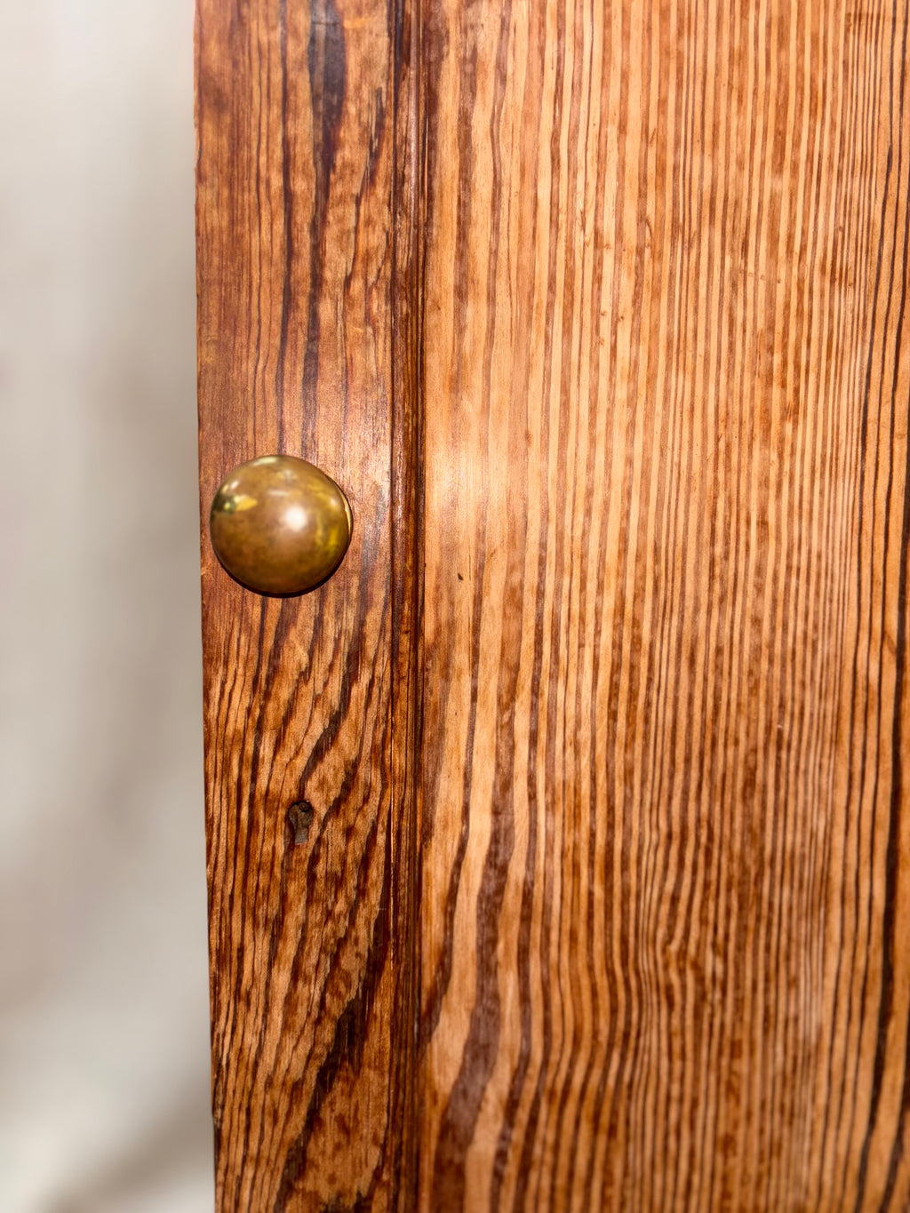 Close-up of a wooden cabinet with a brass knob