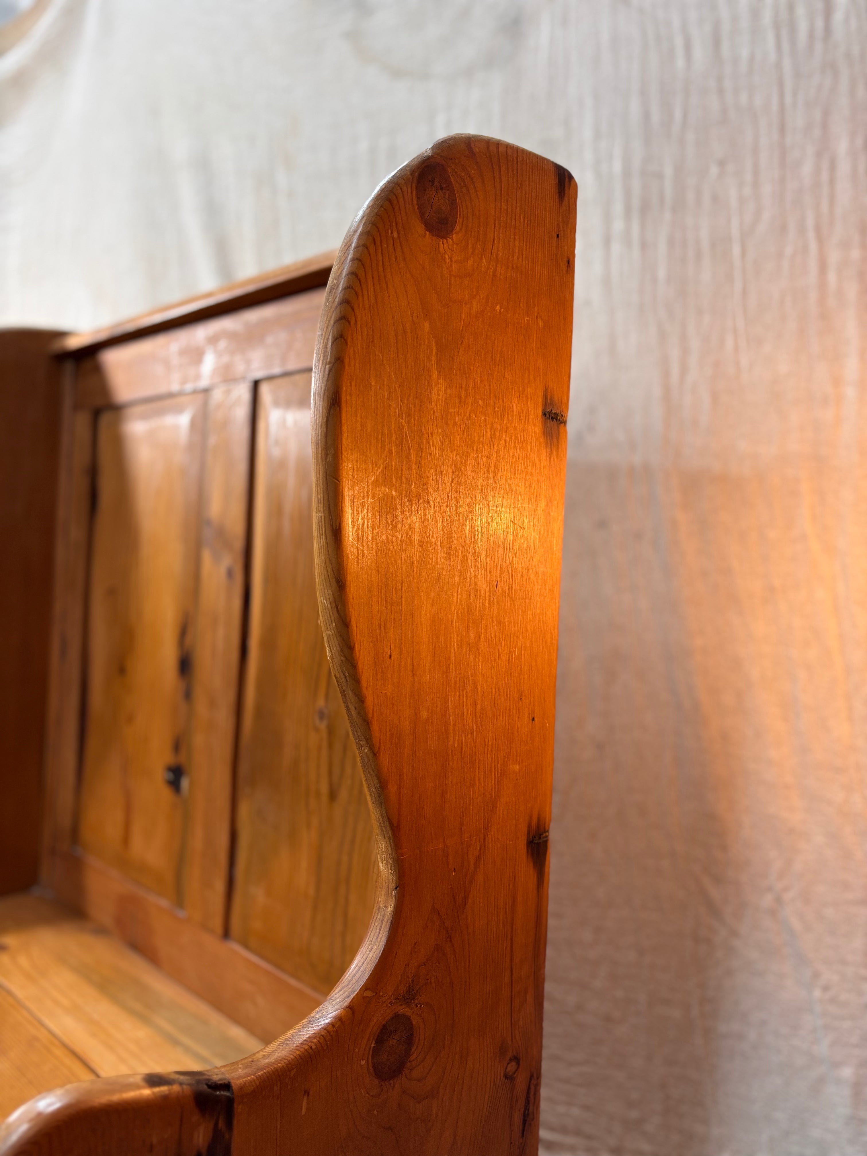 Close-up of a wooden pew with a textured white background