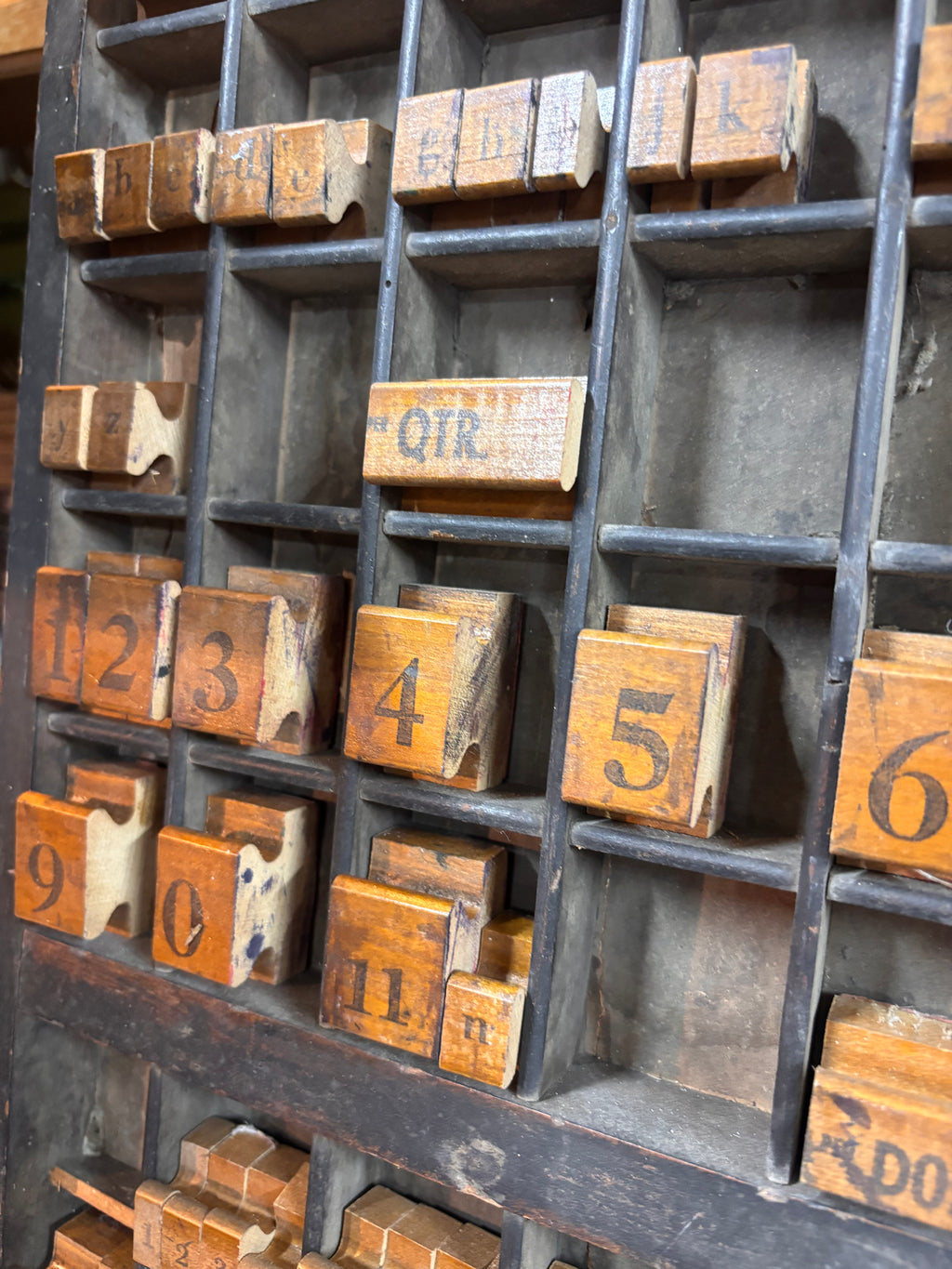 Collection of wooden printing blocks with numbers and letters on a wooden tray.