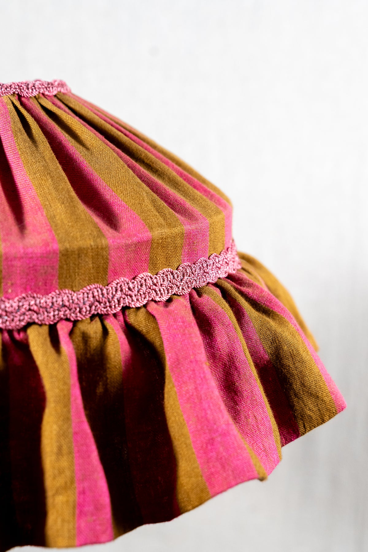 Handmade 12-inch linen carousel shade with raspberry and ochre stripes, vintage trim and pendant fitting. Cosy cottage style.