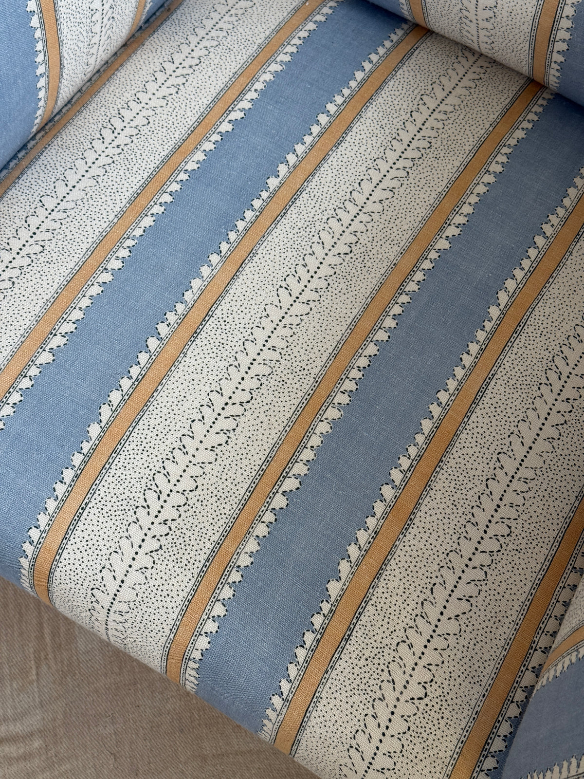 Refurbished antique armchair upholstered in Linwood Dimity ‘Powder Blue’, with a high back, side wings, dark wooden legs and brass casters.