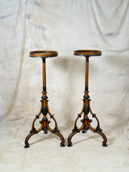 Two ornate dark brown Torchere Stands with decorative scrollwork bases, shown against a draped beige fabric backdrop. 