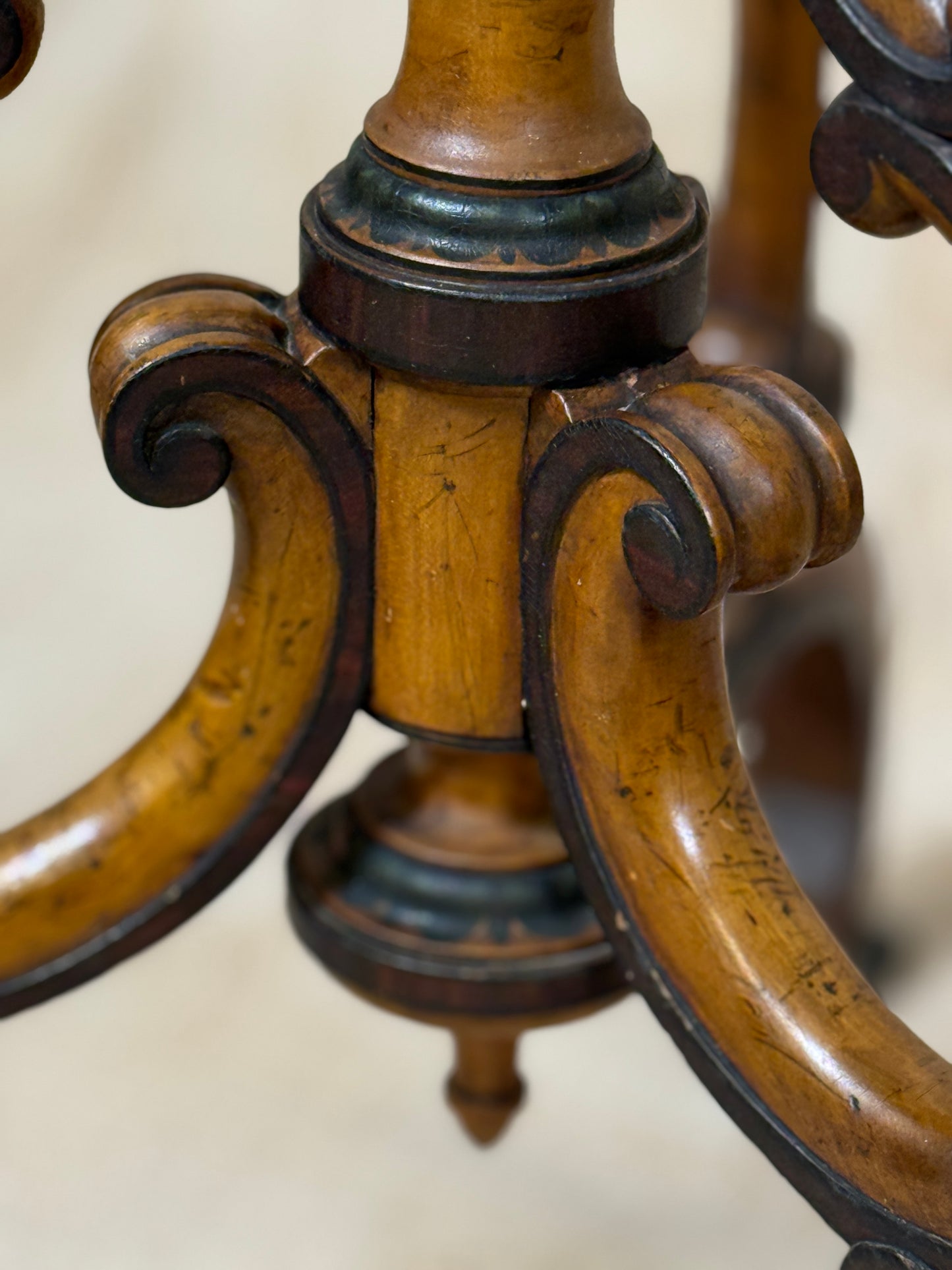 Two ornate dark brown Torchere Stands with decorative scrollwork bases, shown against a draped beige fabric backdrop. 
