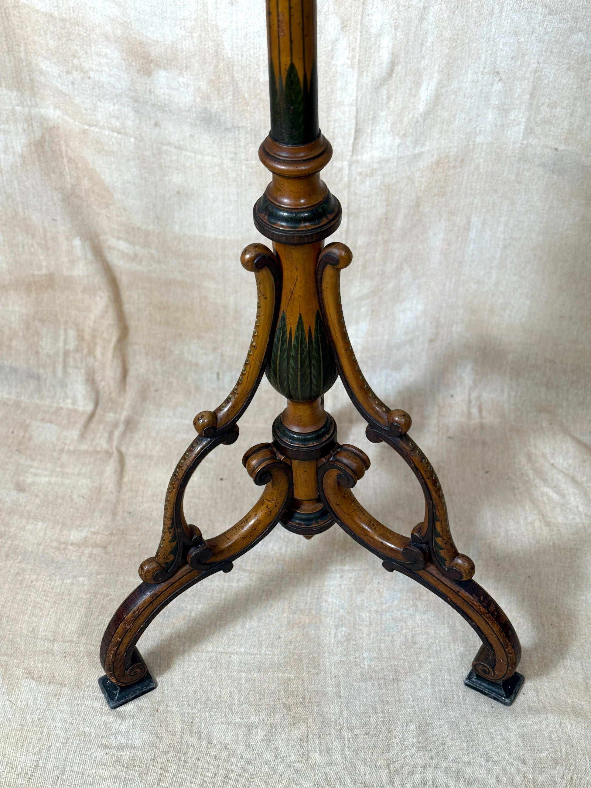 Two ornate dark brown Torchere Stands with decorative scrollwork bases, shown against a draped beige fabric backdrop. 