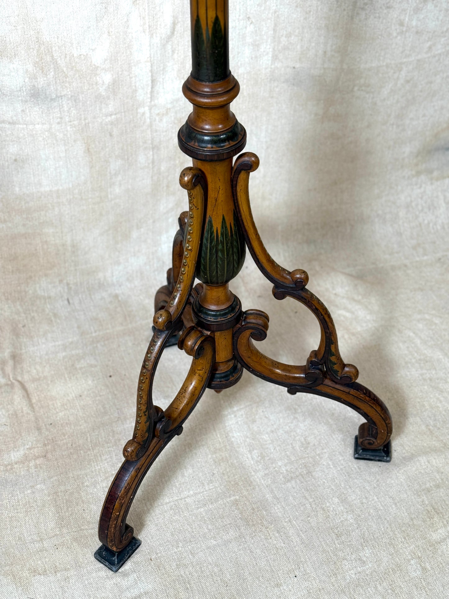 Two ornate dark brown Torchere Stands with decorative scrollwork bases, shown against a draped beige fabric backdrop. 