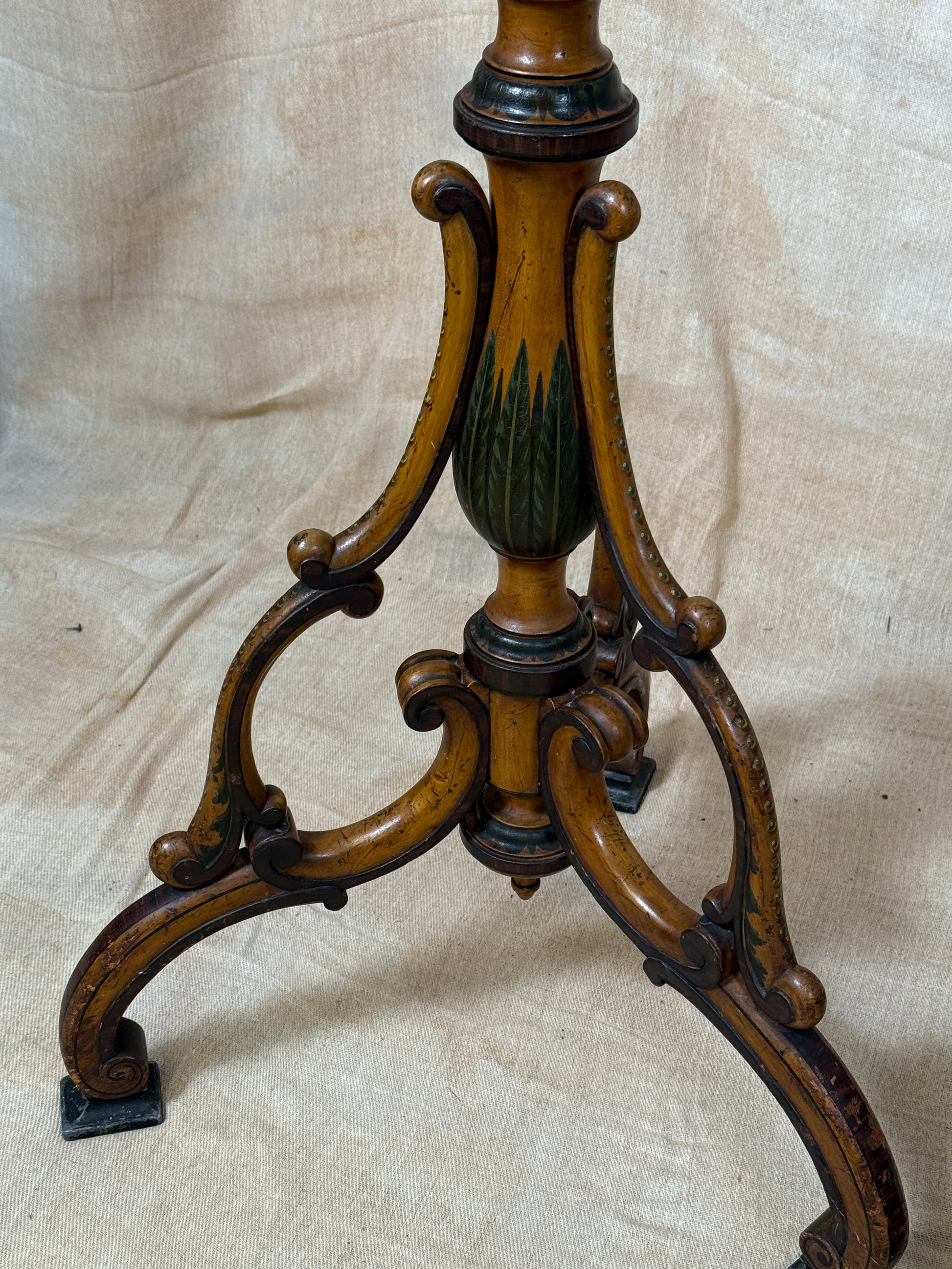 Two ornate dark brown Torchere Stands with decorative scrollwork bases, shown against a draped beige fabric backdrop. 