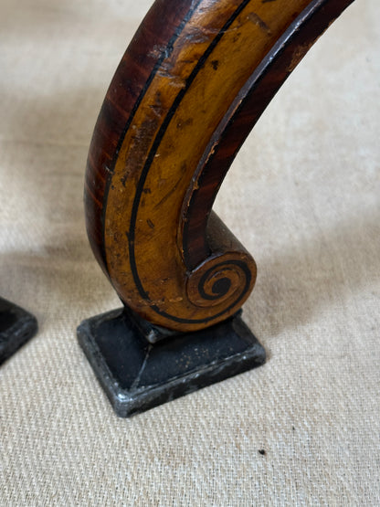 Two ornate dark brown Torchere Stands with decorative scrollwork bases, shown against a draped beige fabric backdrop. 