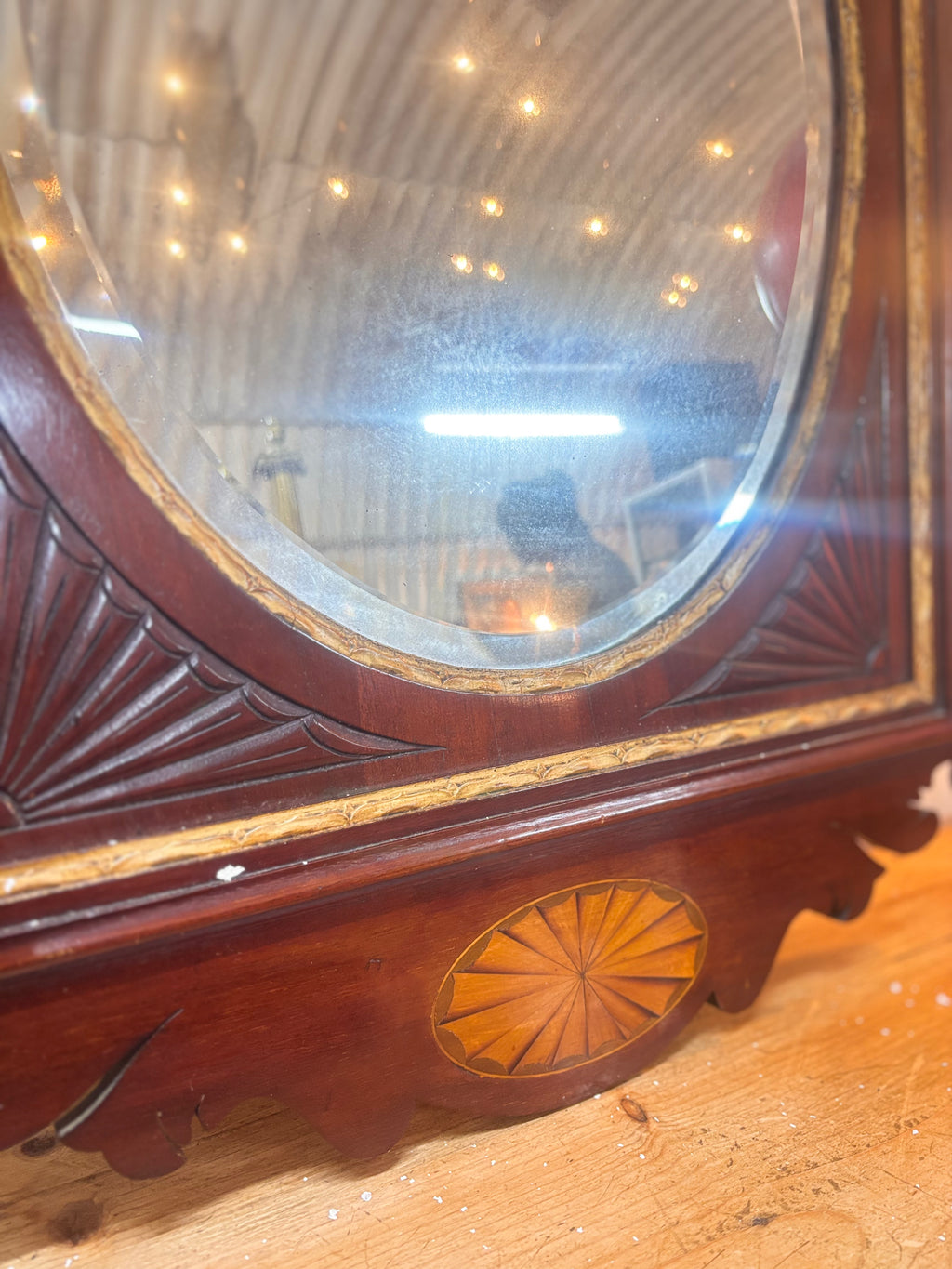 Chippendale revival mahogany mirror with gilded urn crest, carved fretwork, and oval plate in a rectangular frame