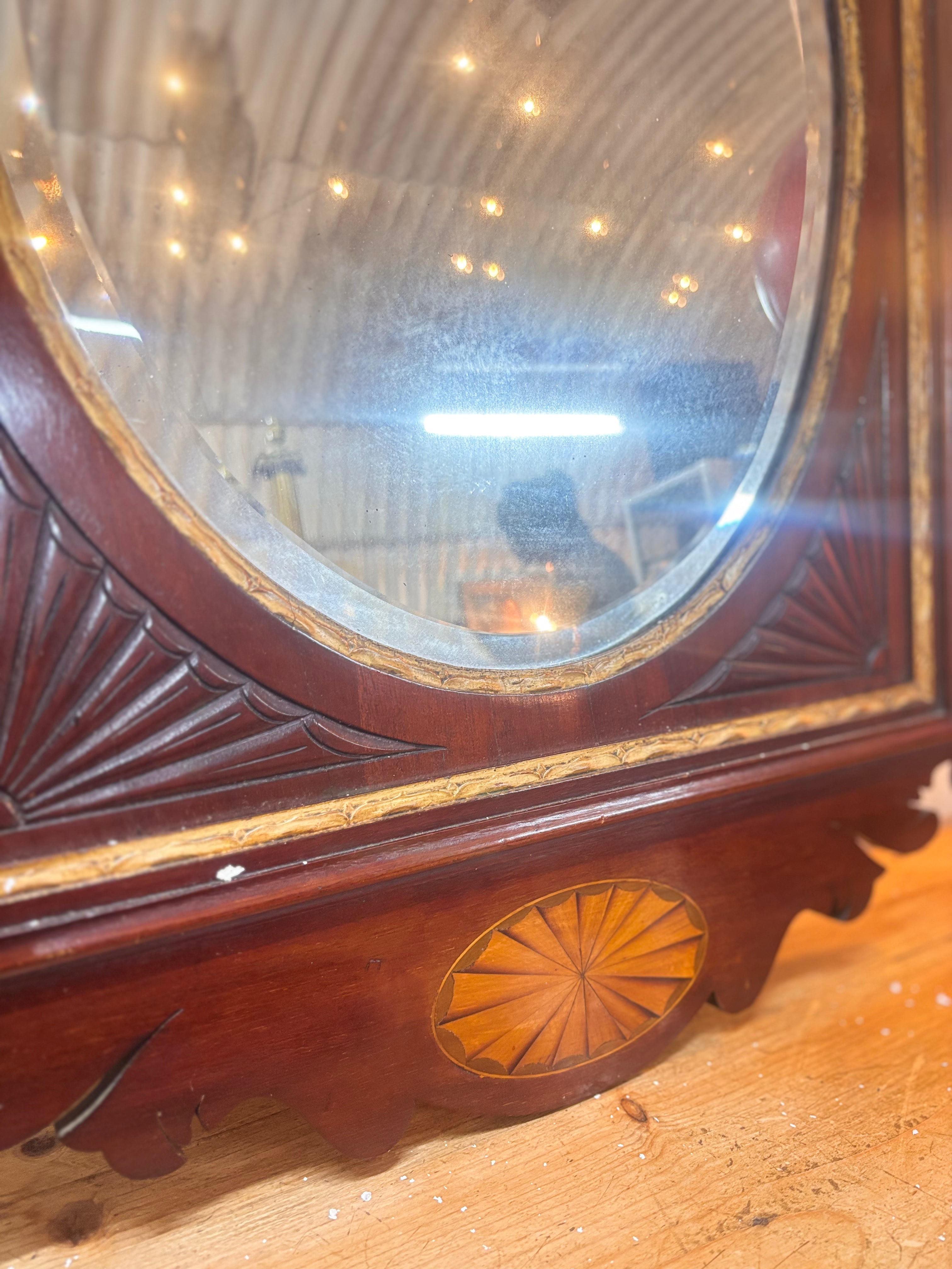 Chippendale revival mahogany mirror with gilded urn crest, carved fretwork, and oval plate in a rectangular frame