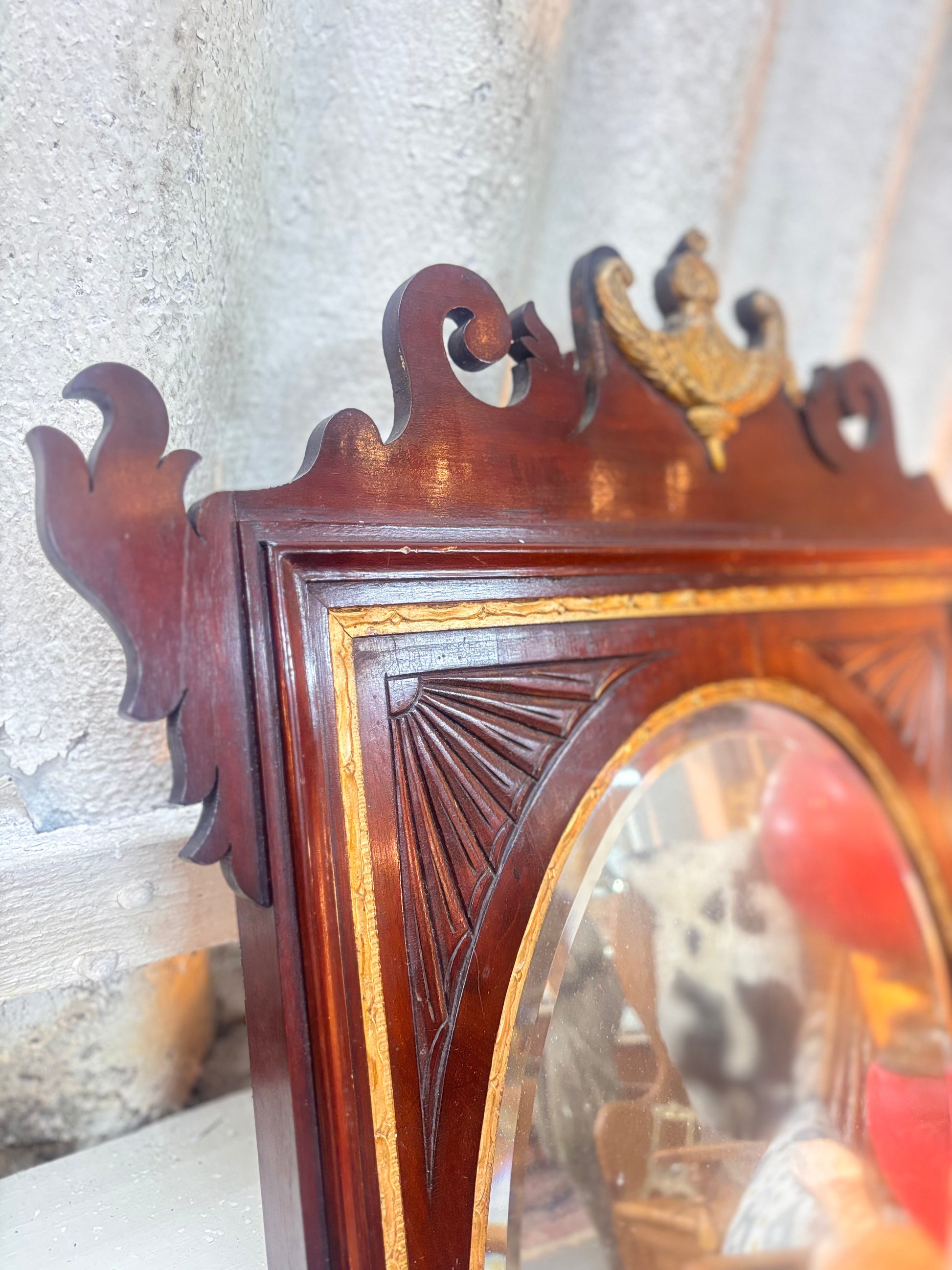 Chippendale revival mahogany mirror with gilded urn crest, carved fretwork, and oval plate in a rectangular frame