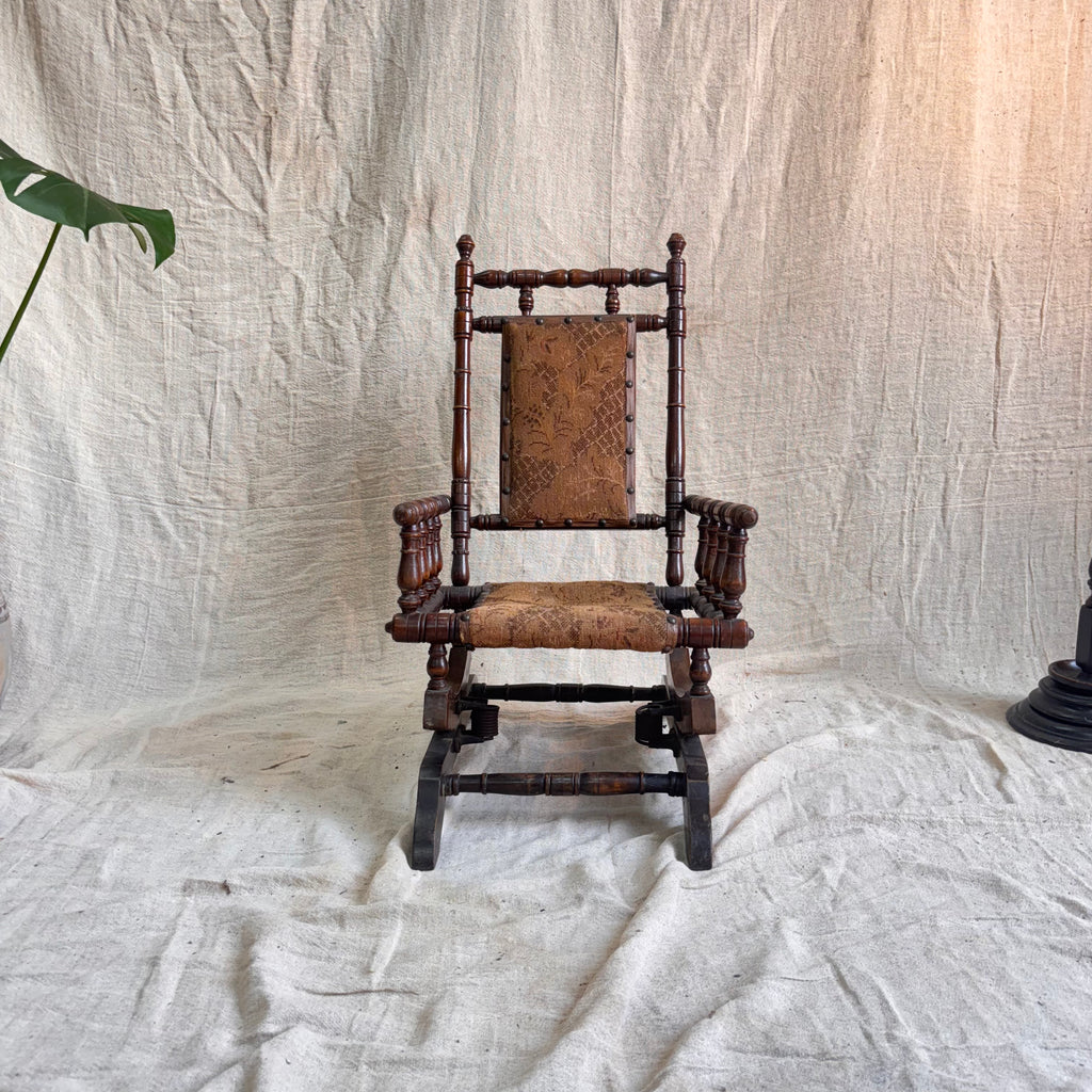 Wooden rocking chair with a patterned cushion on a white draped background