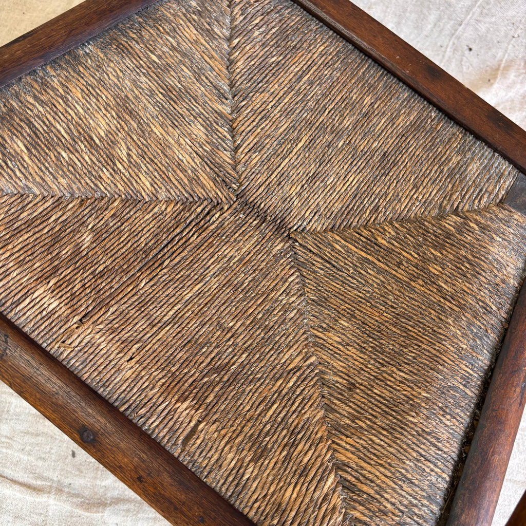 Close-up of a wooden chair with a rush seat pad. 