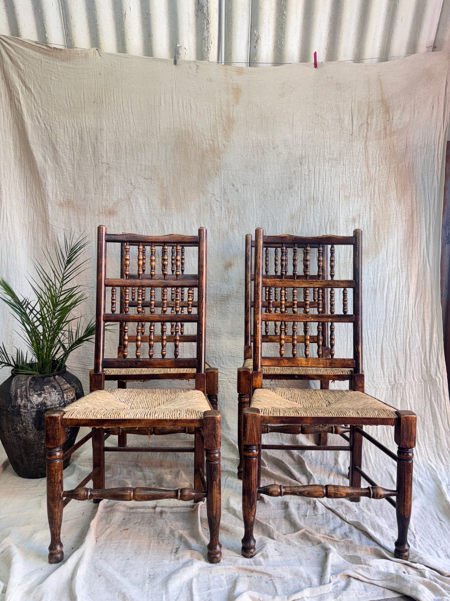 Four Wooden Chairs on a textured surface with a white cloth in the background