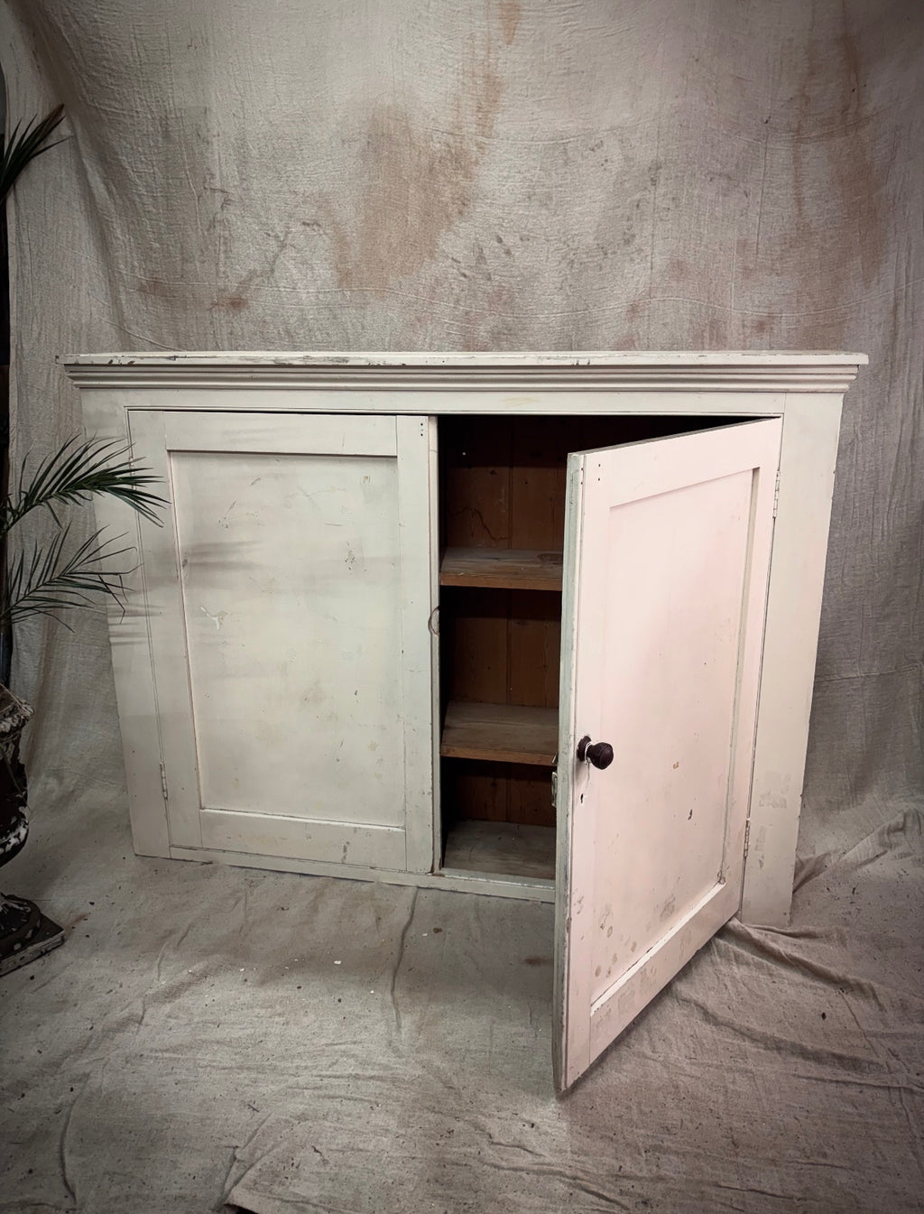 Vintage-style wooden cabinet with open door on a textured gray background