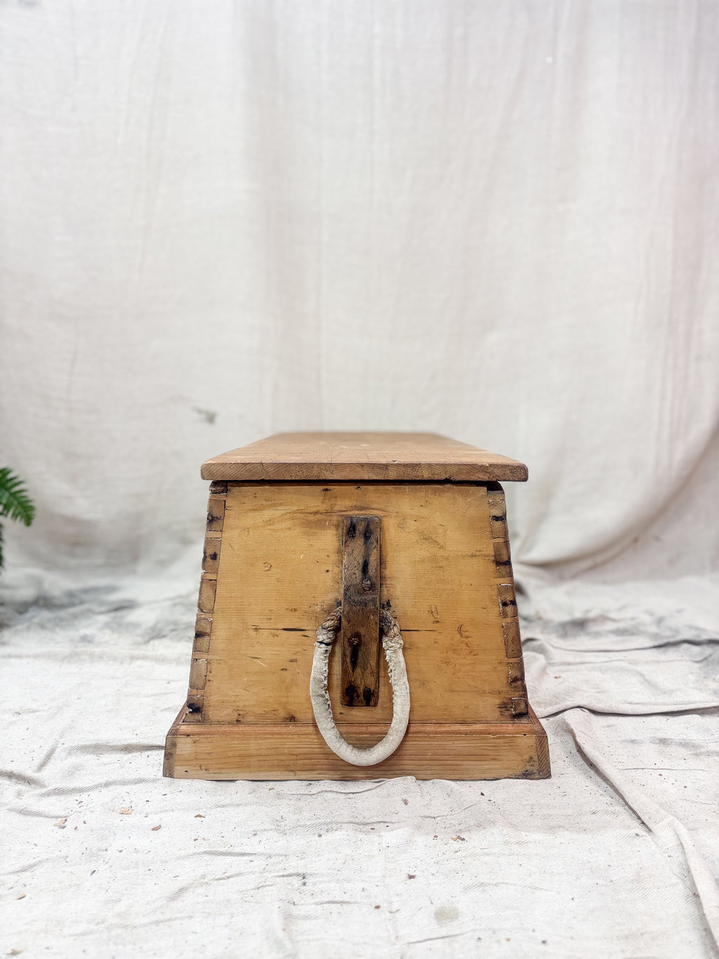 Wooden box with a rope handle on a white fabric background