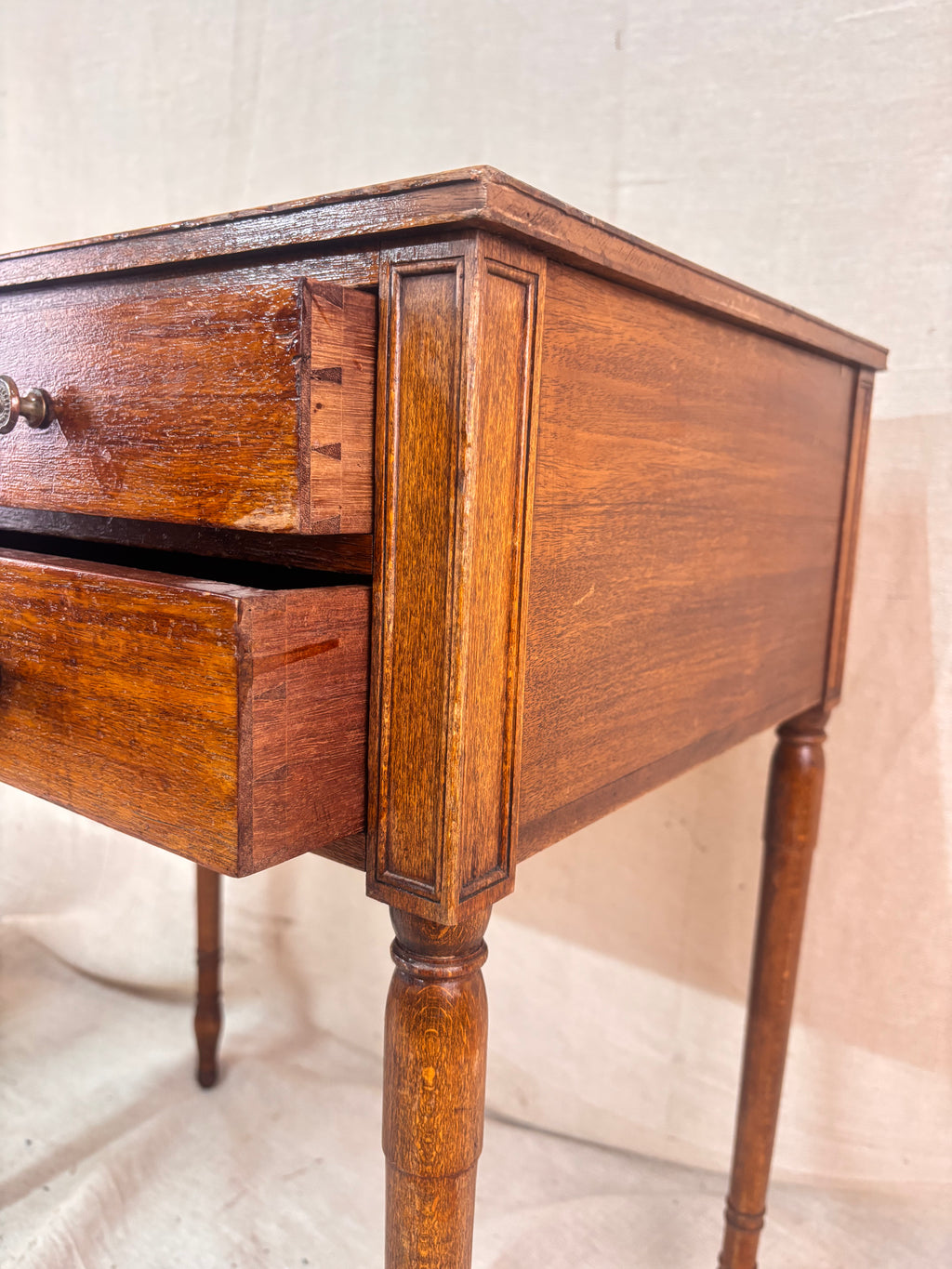 Regency-style mahogany side table with two drawers, slender ring-turned legs, and a neo-classical design, shown on a neutral background.
