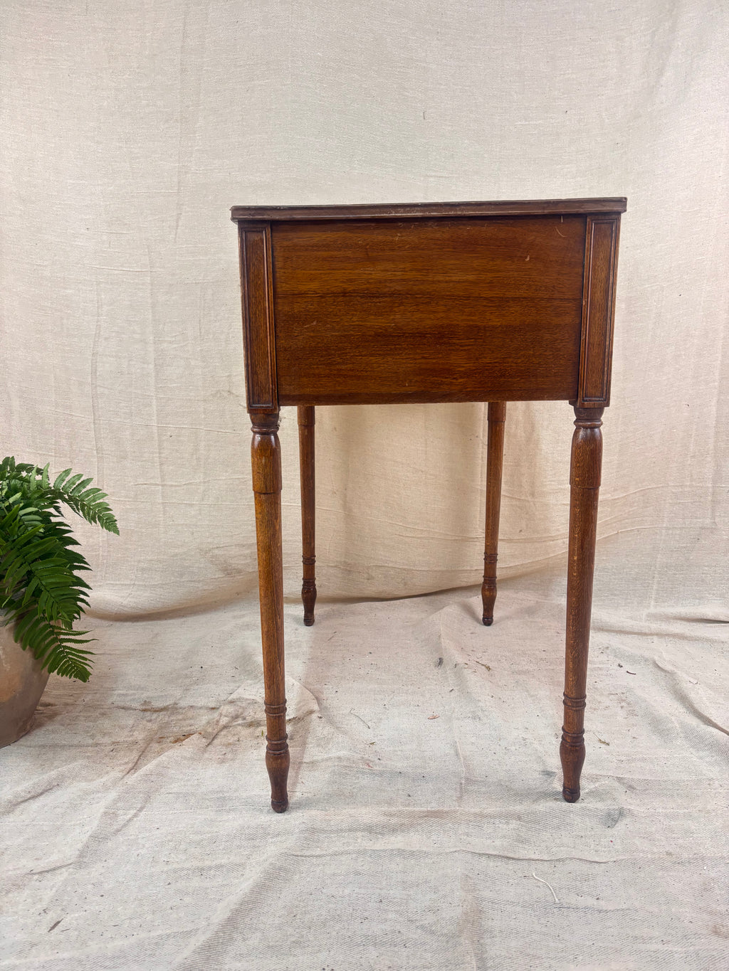 Regency-style mahogany side table with two drawers, slender ring-turned legs, and a neo-classical design, shown on a neutral background.