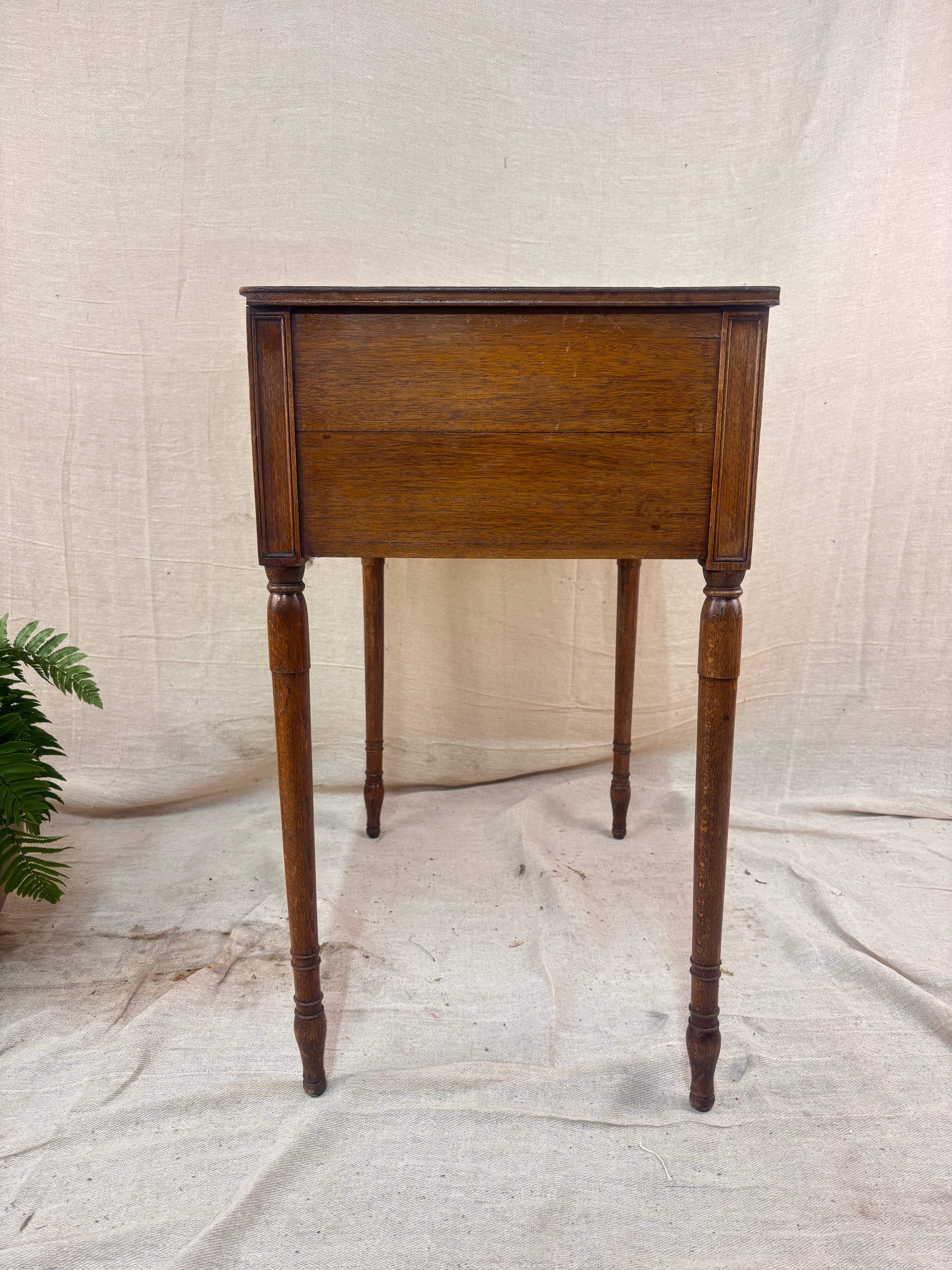 Regency-style mahogany side table with two drawers, slender ring-turned legs, and a neo-classical design, shown on a neutral background.