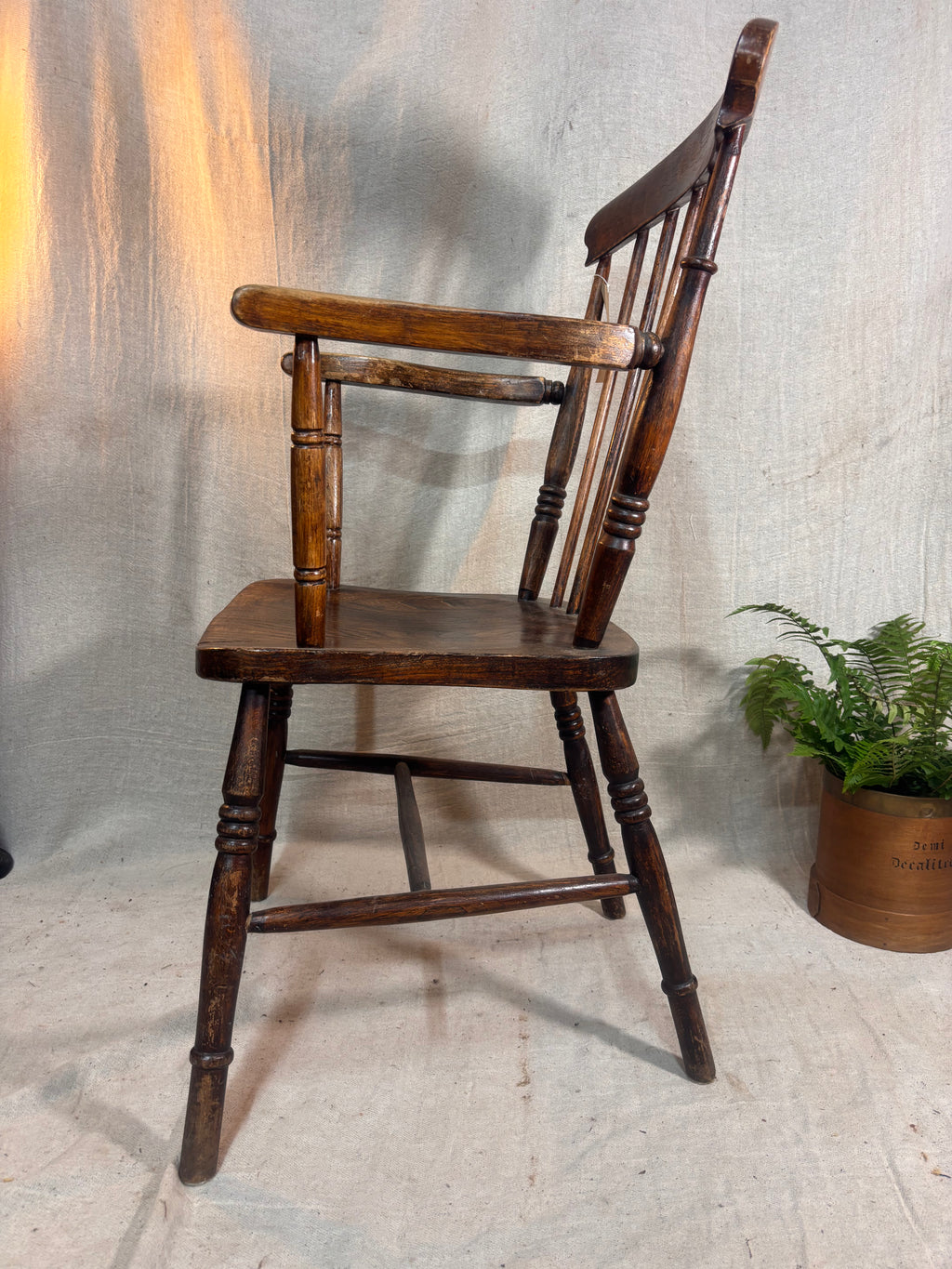 Wooden chair with a plant in the background on a textured surface